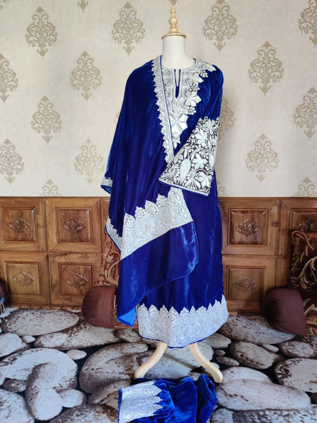Full view of the royal-blue velvet pheran set with a draped stole, crossed sleeve and matching trousers below the mannequin.