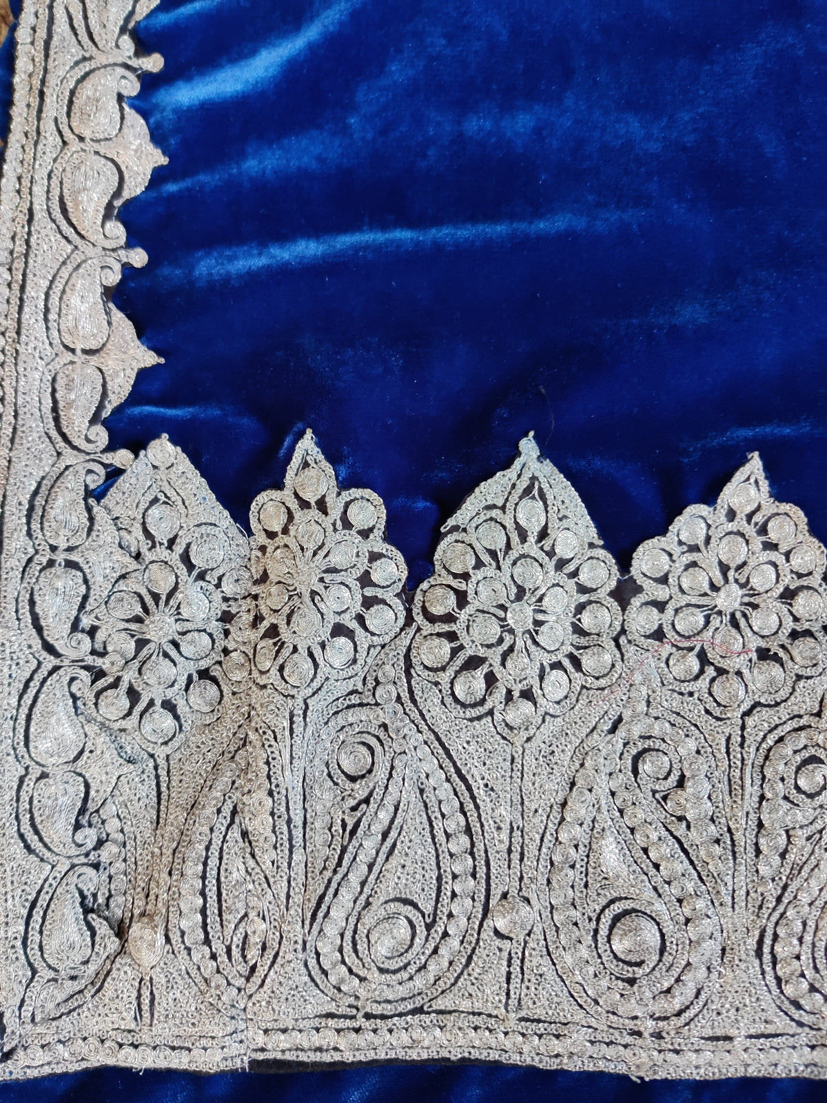 Flat corner detail of the blue velvet stole with silver-toned paisleys and rosettes meeting a narrow scrolling border.