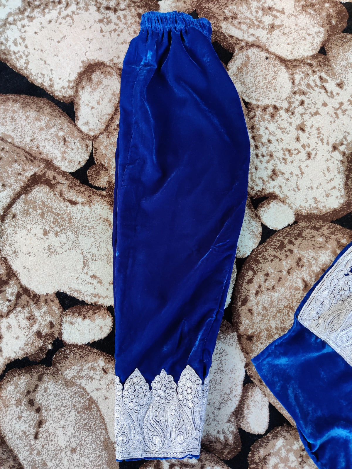 Matching royal-blue trousers laid flat, with an elastic waist and a broad silver-toned embroidered ankle border.