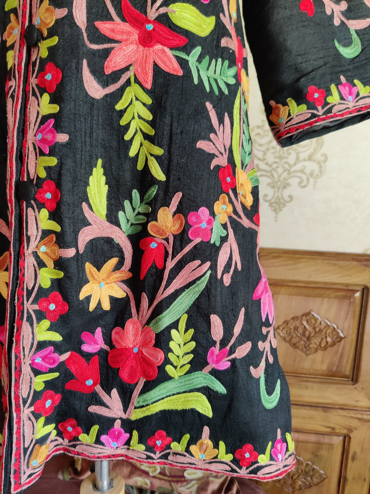 Black jacket front and sleeve detail with pink Aari stems, red flowers, yellow blossoms and green leaves