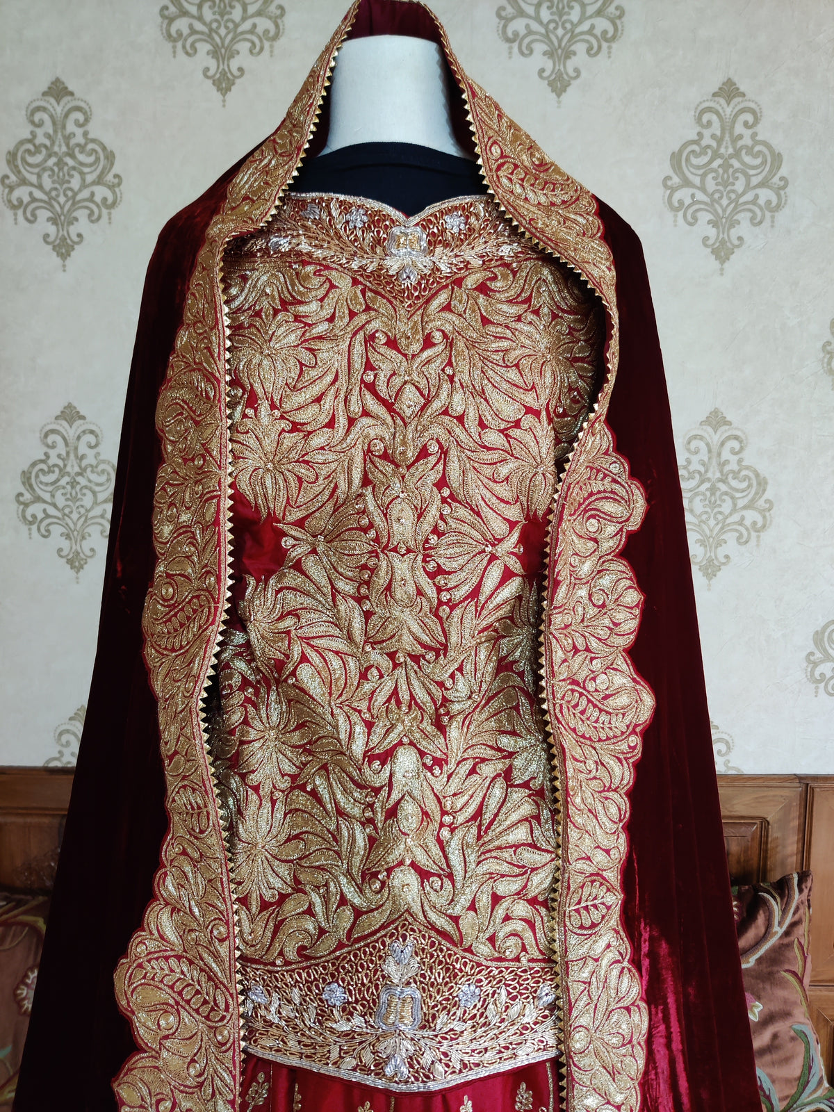 Close-up of the red top covered in golden Tilla leaf and floral embroidery, framed by the maroon dupatta’s ornate edges