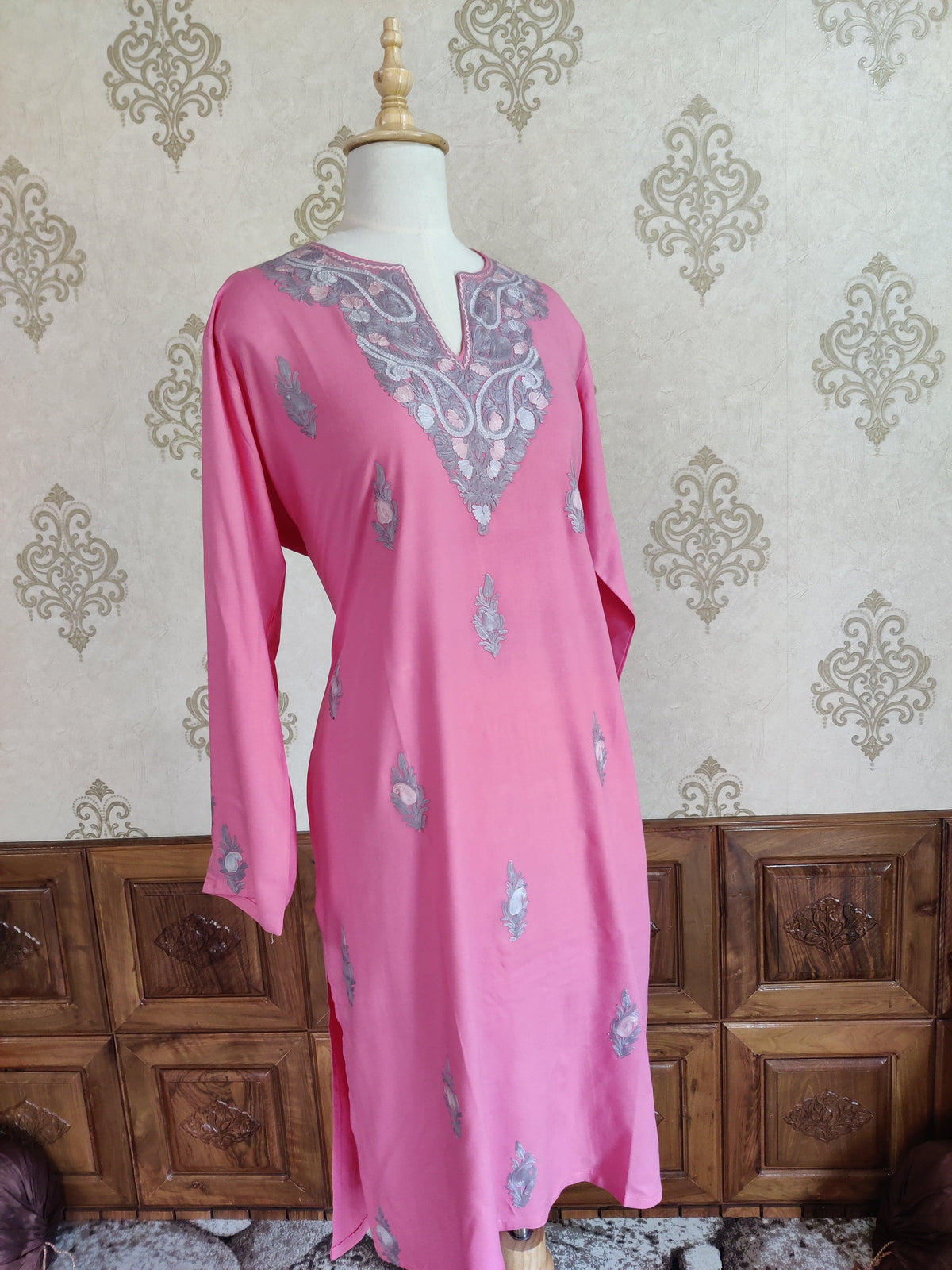 Pink long-sleeved kurti on a mannequin, with a grey and cream Aari neckline and small motifs across the front
