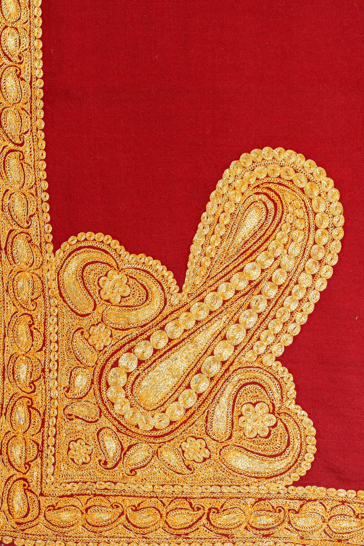 Detail of a large golden paisley Tilla motif meeting the corner borders of the red Merino wool shawl