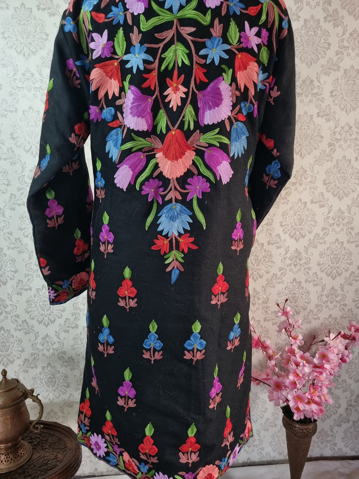 Closer back view of the black jacket, showing its colourful V-shaped flower arrangement and scattered small floral sprigs.