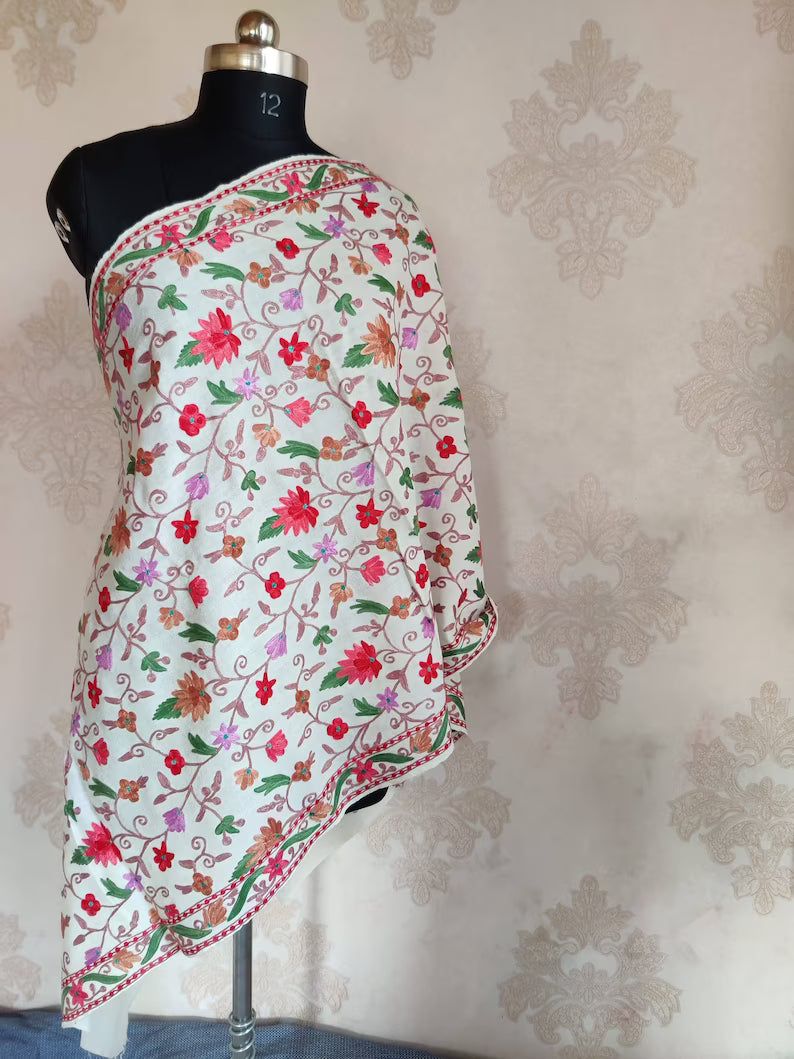 Full view of a white merino wool stole on a mannequin, covered in colourful floral vines with a narrow embroidered border.