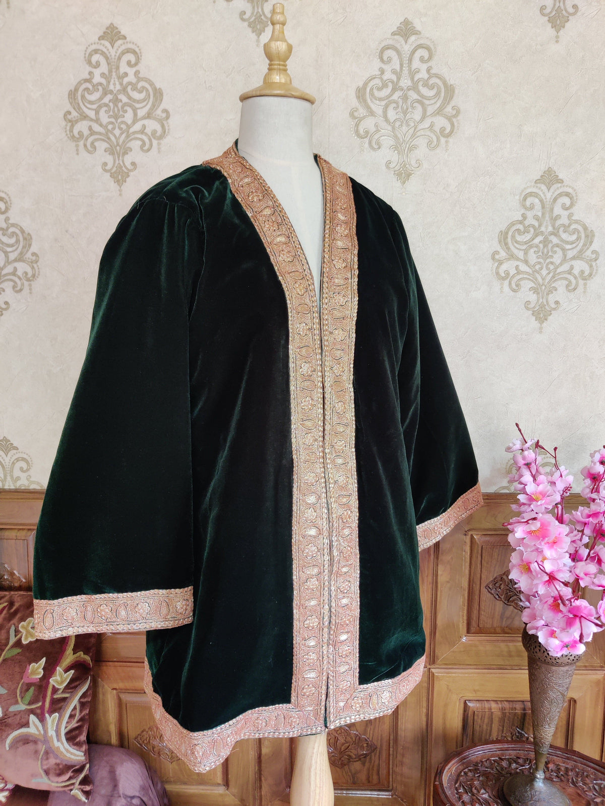 Angled view of a dark green kimono robe on a mannequin, with loose wide sleeves and gold-toned Tilla floral borders.