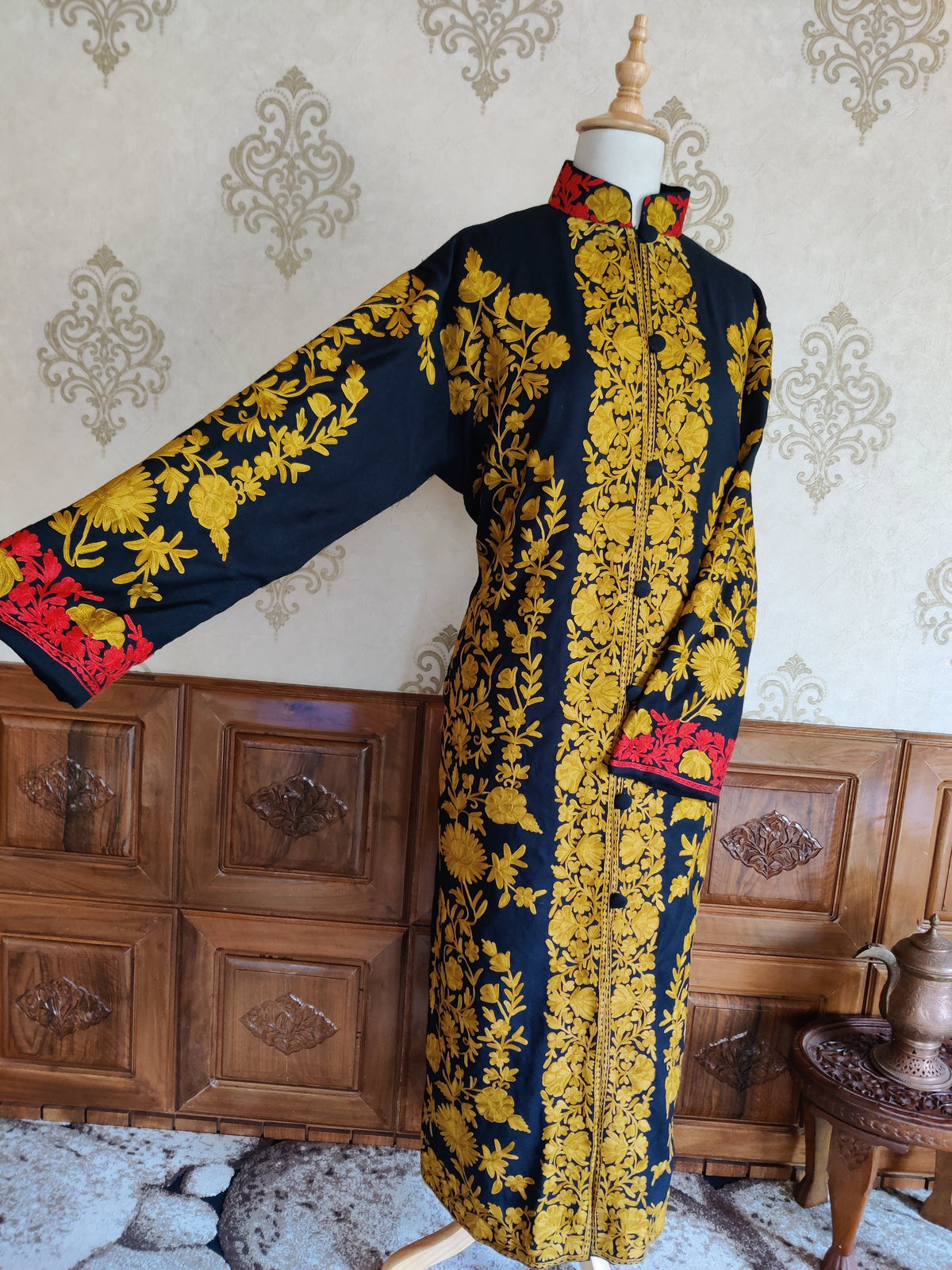 Navy jacket with one sleeve extended, showing mustard-yellow floral trails and a red embroidered cuff.