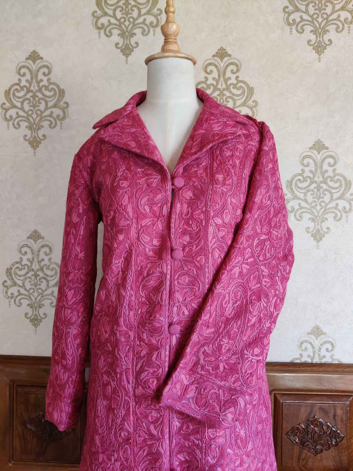 Front of the pink Aari jacket with a notched collar, covered buttons and one sleeve folded inward.