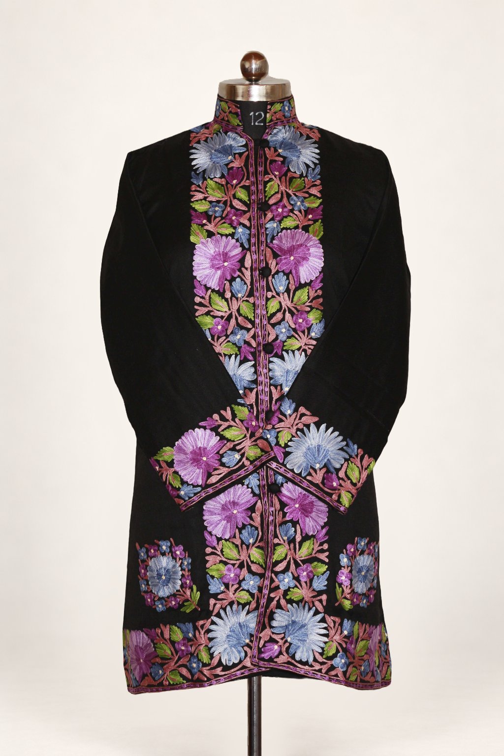 Front view of a black long jacket with lilac, pink and pale blue Aari flowers along the front, crossed cuffs and hem