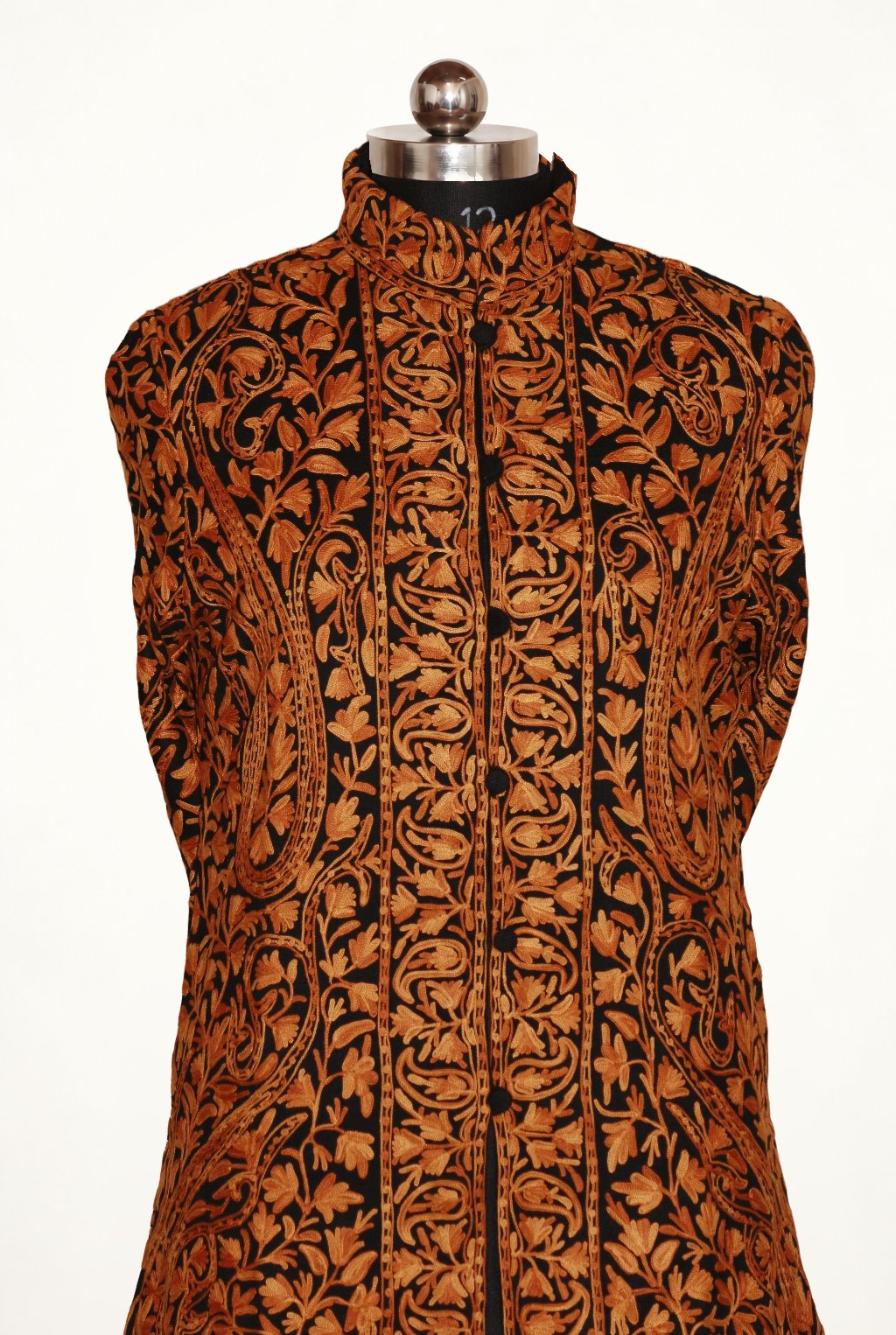 Front view of the black jacket on a mannequin, with dense orange-brown Aari paisley embroidery and a stand collar