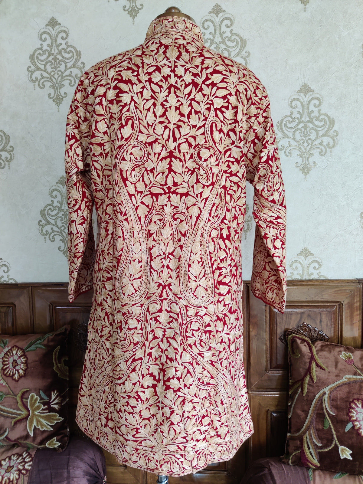 Back view of a maroon woollen jacket with dense cream vines and two large symmetrical paisley motifs.