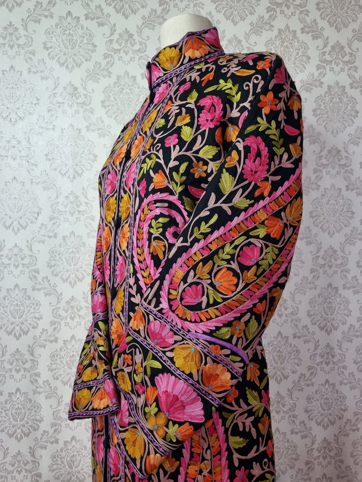 Close-up of the black jacket’s shoulder and crossed sleeve, with pink and orange flowers inside a large paisley outline.