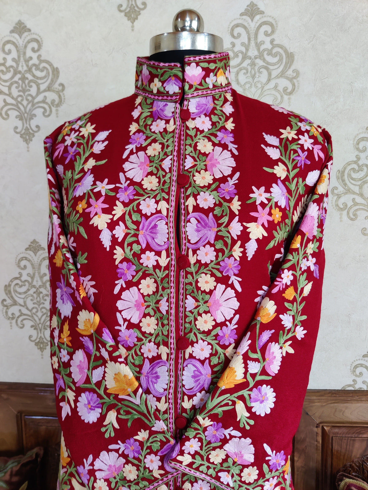 Upper front detail of a maroon jacket with pink and lavender flowers, green leafy vines and an embroidered stand collar.