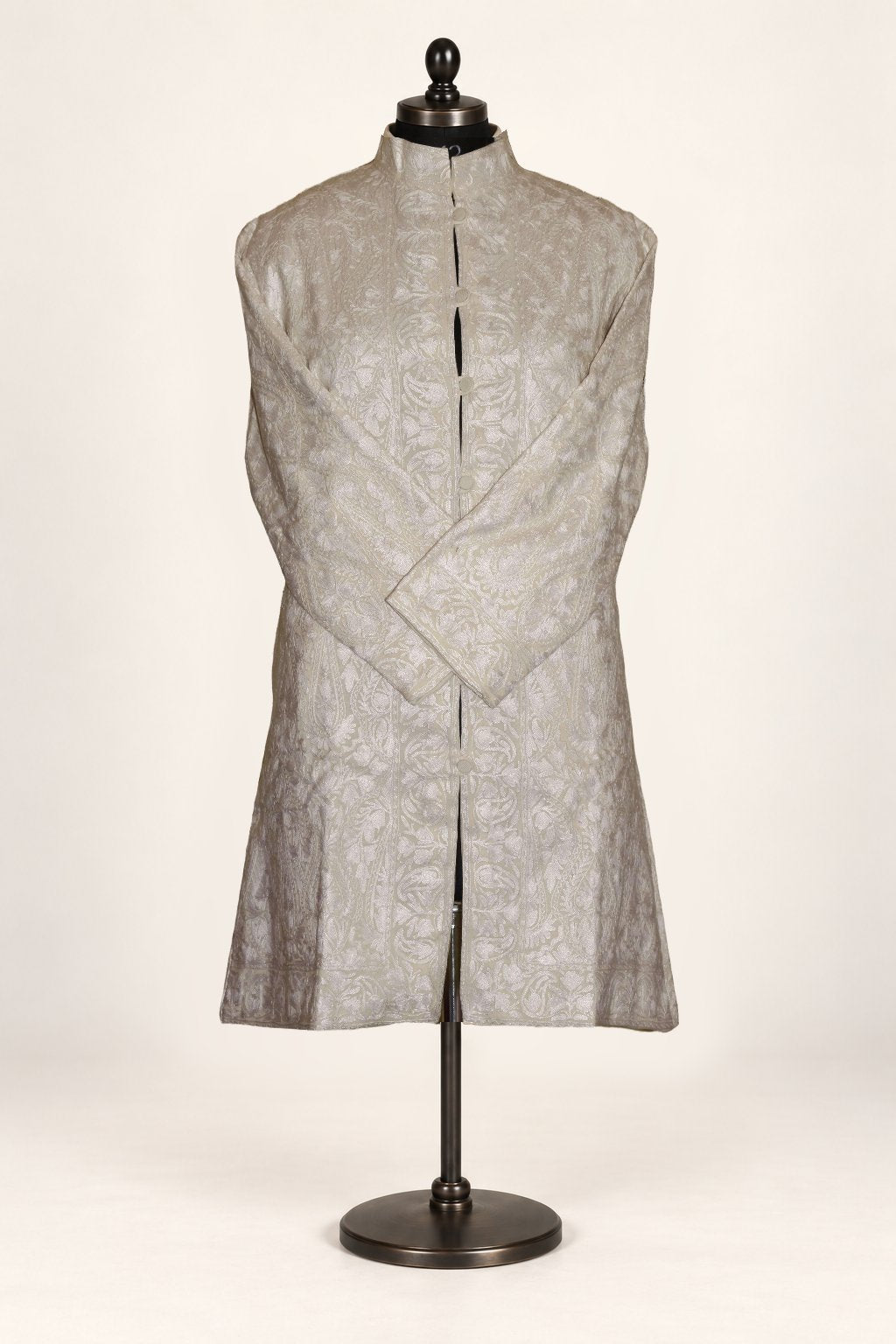 White Kashmiri jacket on a mannequin, with tonal Aari paisley embroidery, a band collar and crossed sleeves