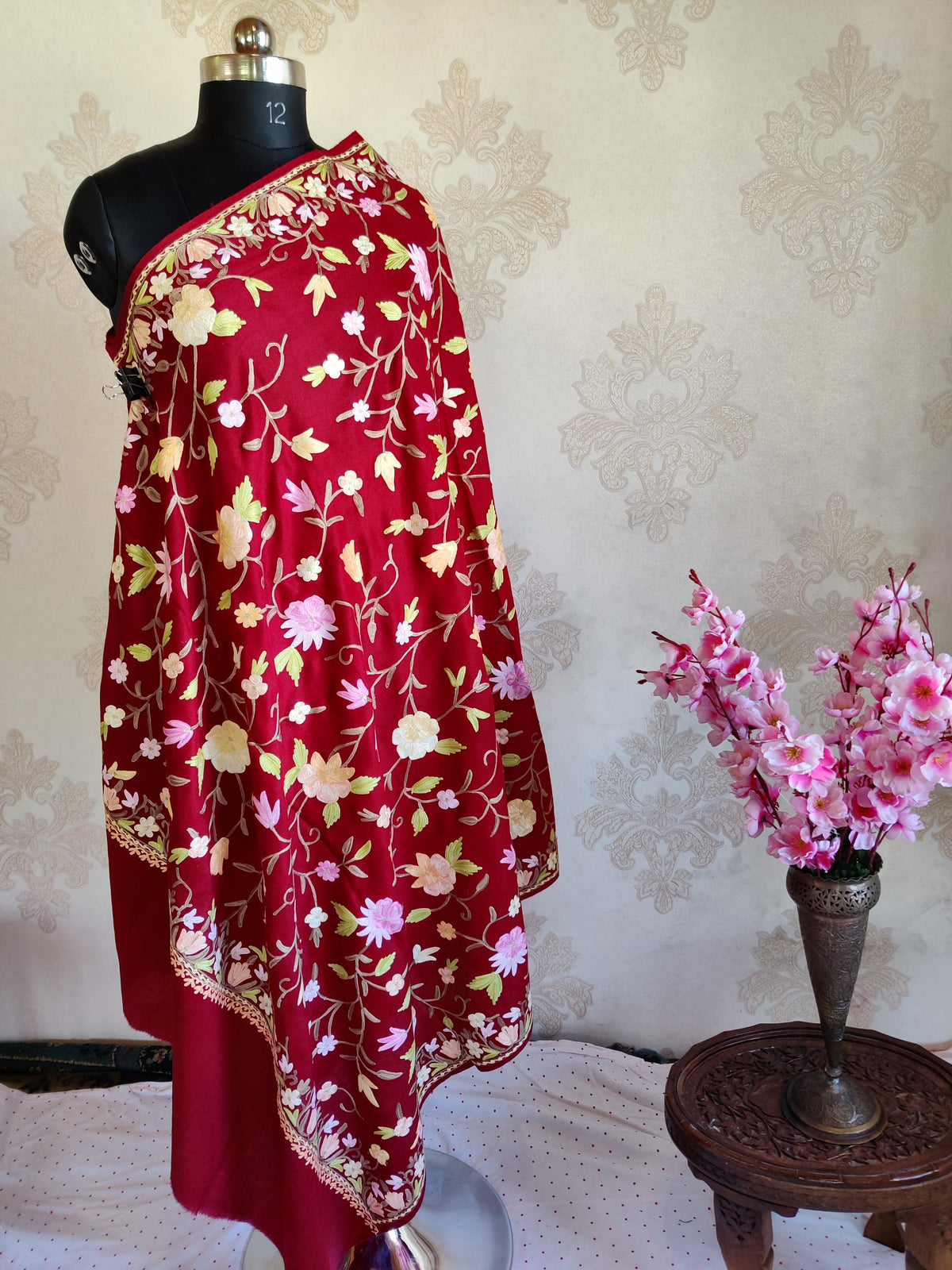 Maroon merino wool stole draped full length on a mannequin, showing all-over pastel floral vines and a narrow floral border.