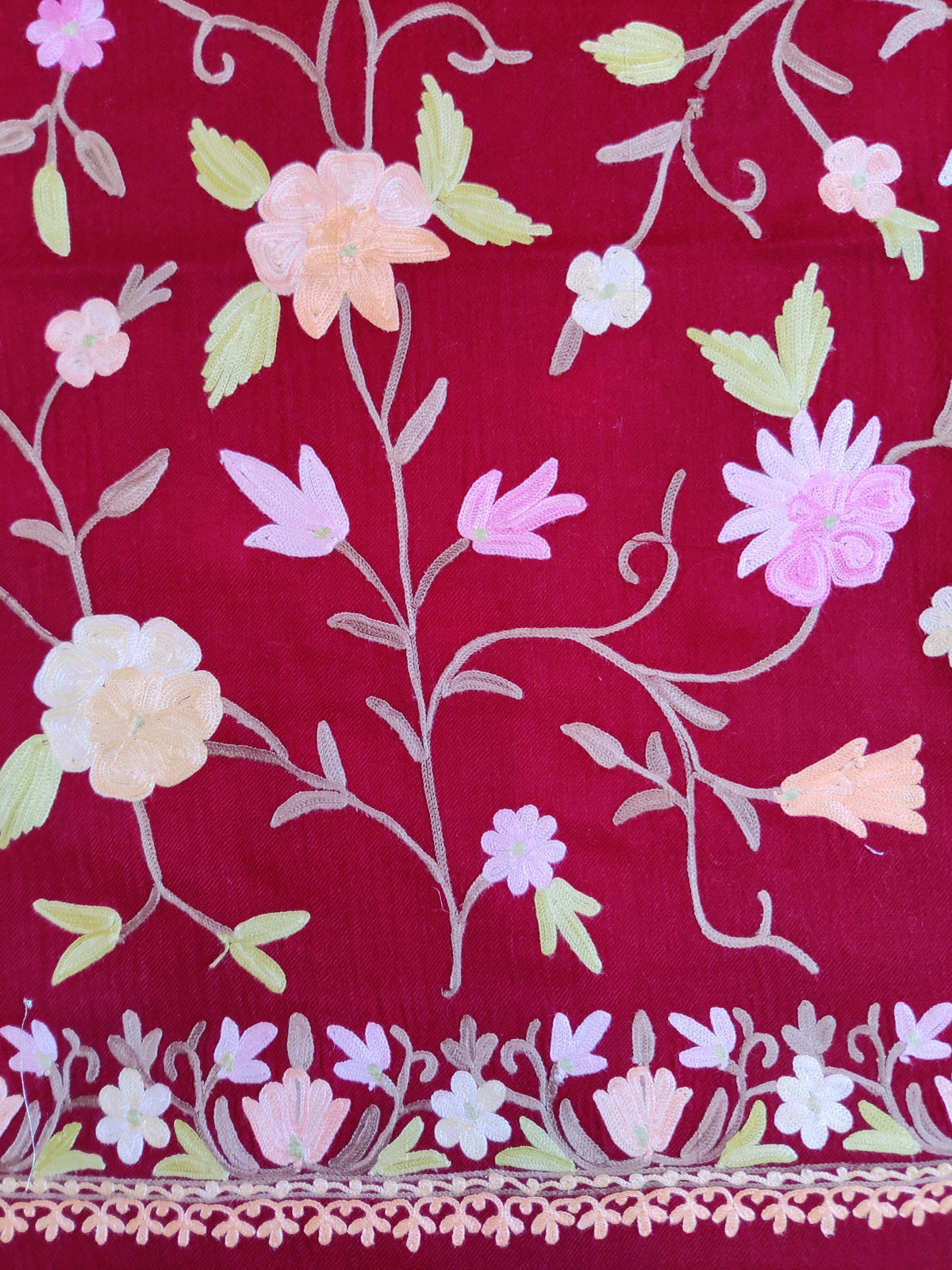 Close-up of pastel flowers and curling stems on the maroon stole, with a small floral border along the edge.
