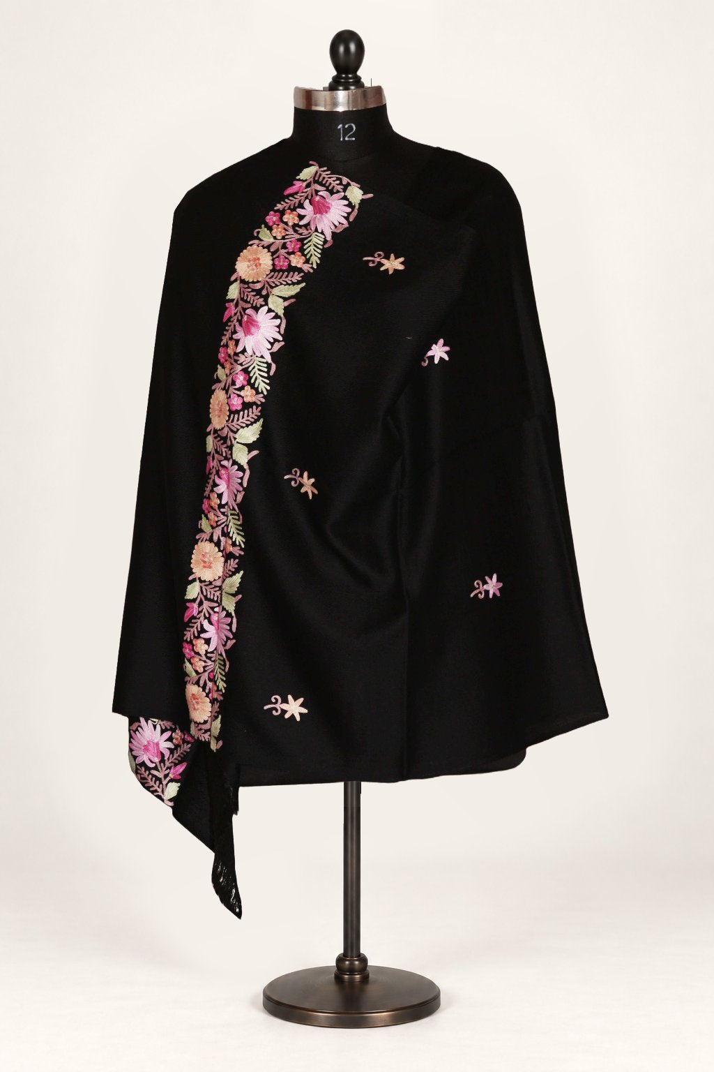 Black merino wool stole wrapped on a mannequin, with scattered small Aari floral sprigs and a pink, cream and green floral border.