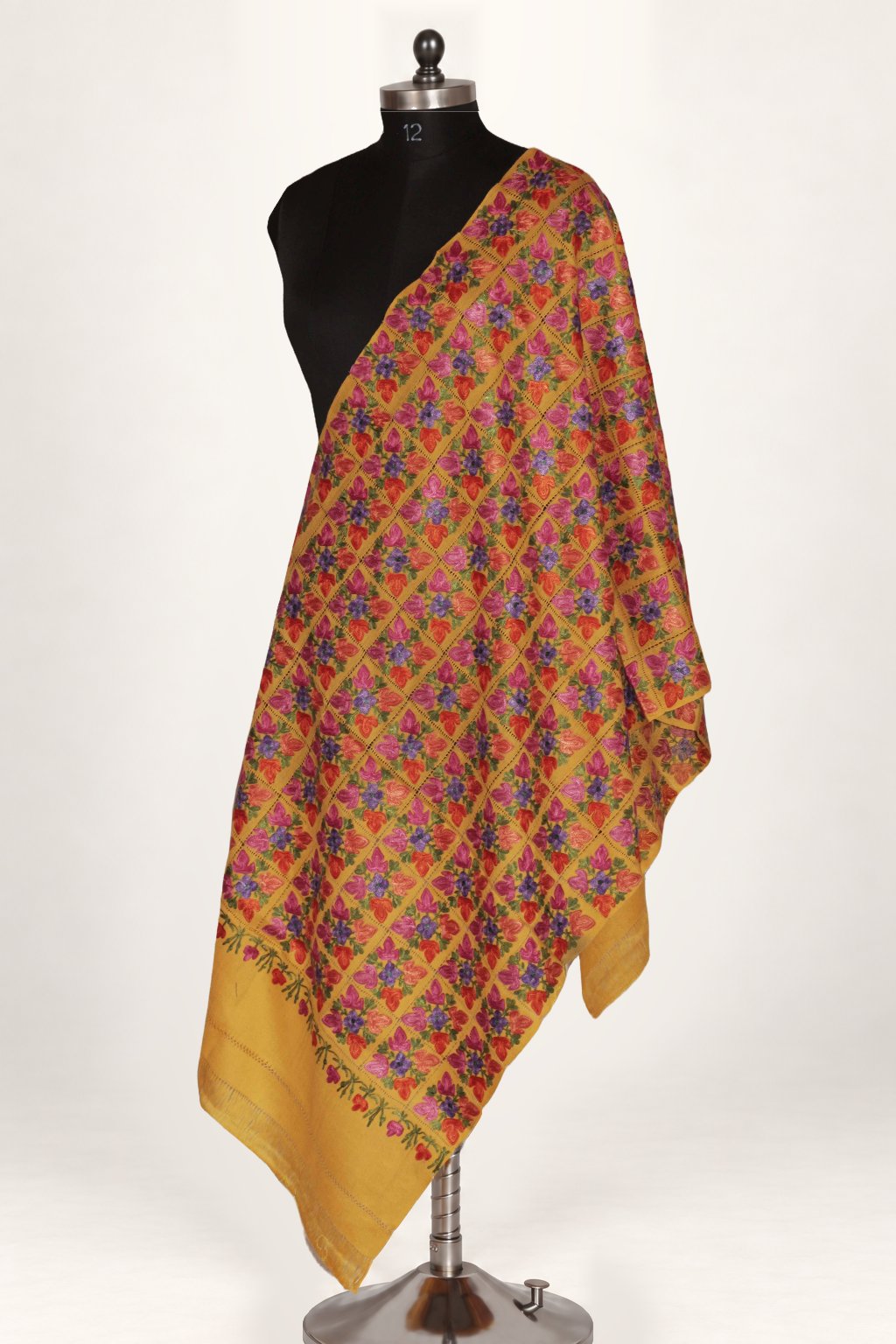 Yellow Merino wool stole draped on a mannequin, with a dense multicoloured floral Aari cutwork pattern