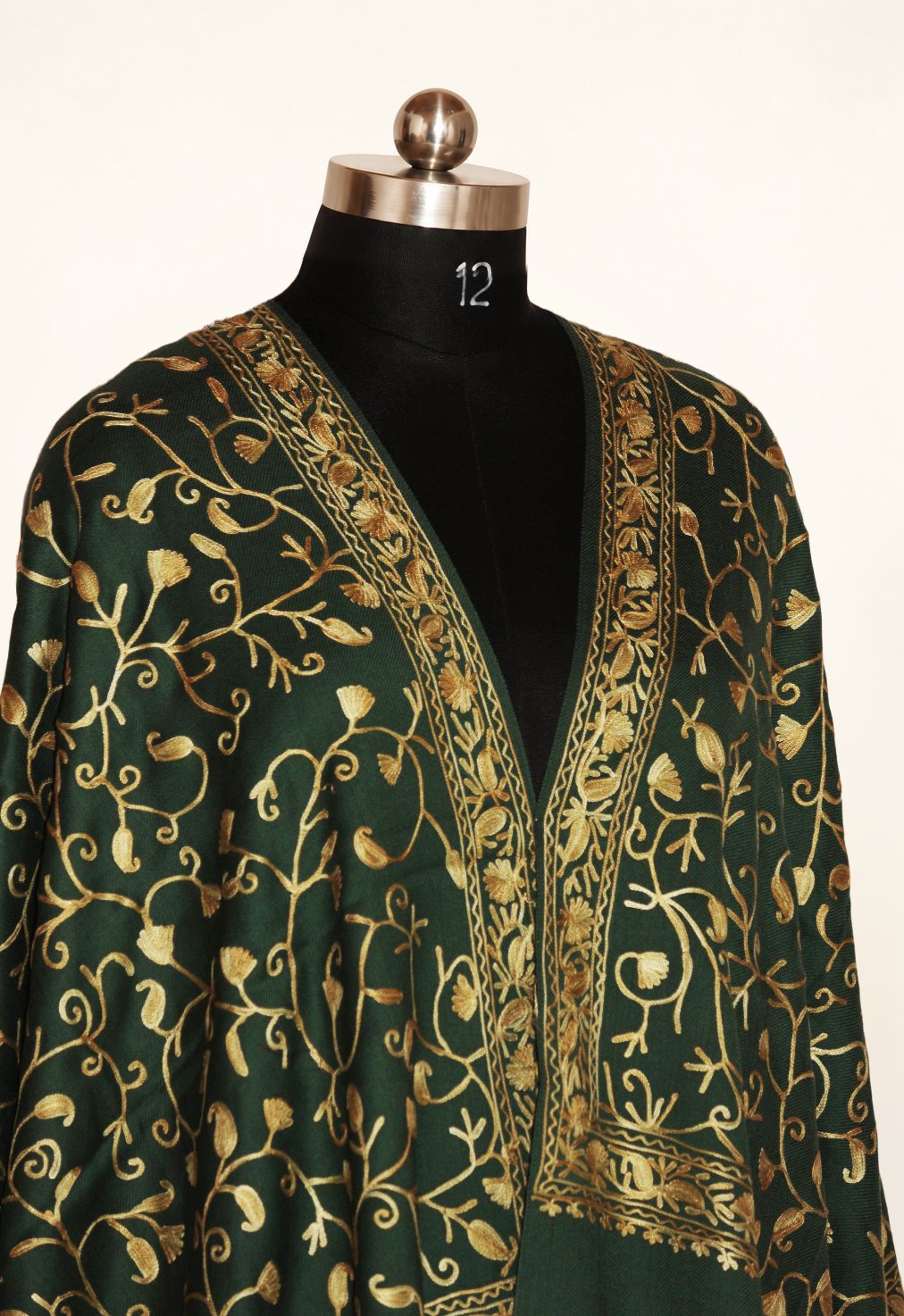 Upper view of a green Merino wool stole on a mannequin, with gold-toned Aari scrolling vines and narrow floral borders