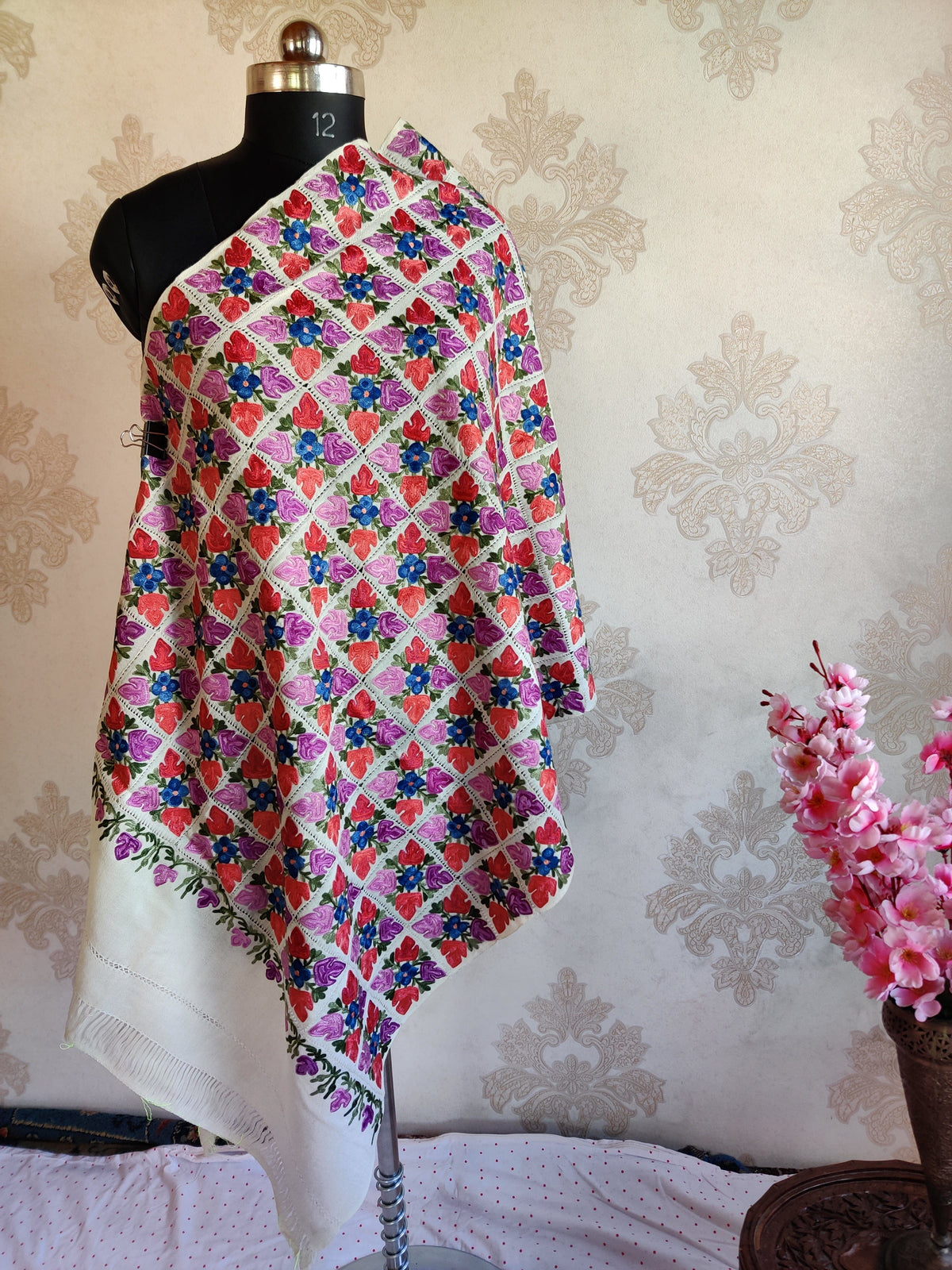 White Merino wool stole draped on a mannequin, with vivid pink, purple and blue floral cutwork above a plain white end