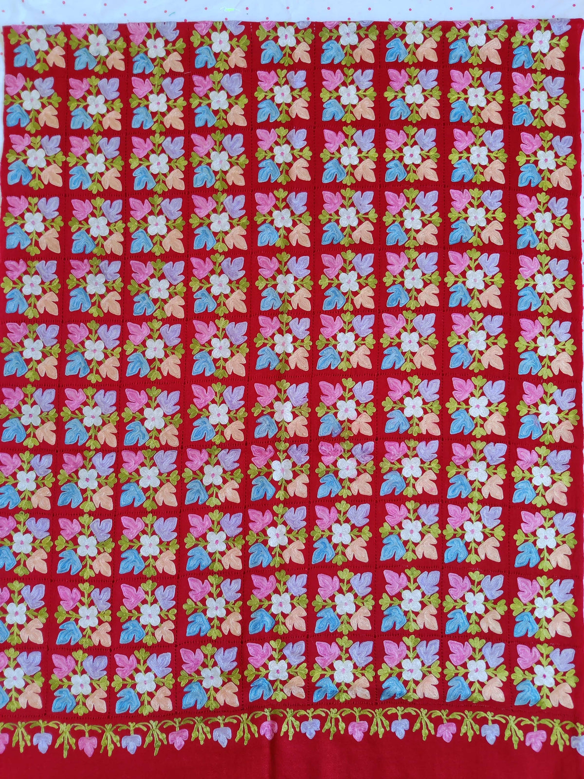 Red stole laid flat, showing a grid of pastel floral motifs and a small trailing-flower border.