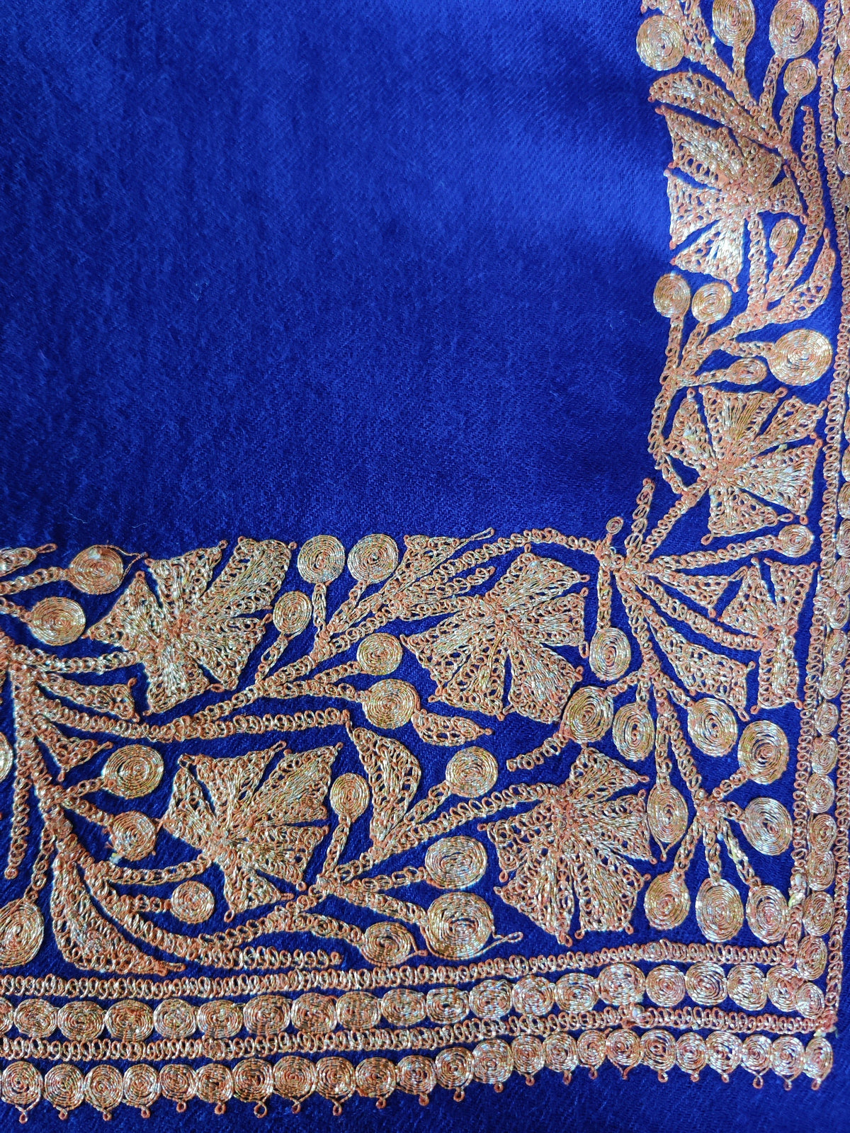 Flat corner detail of the blue stole, showing a gold-toned leafy border with rows of small round motifs.