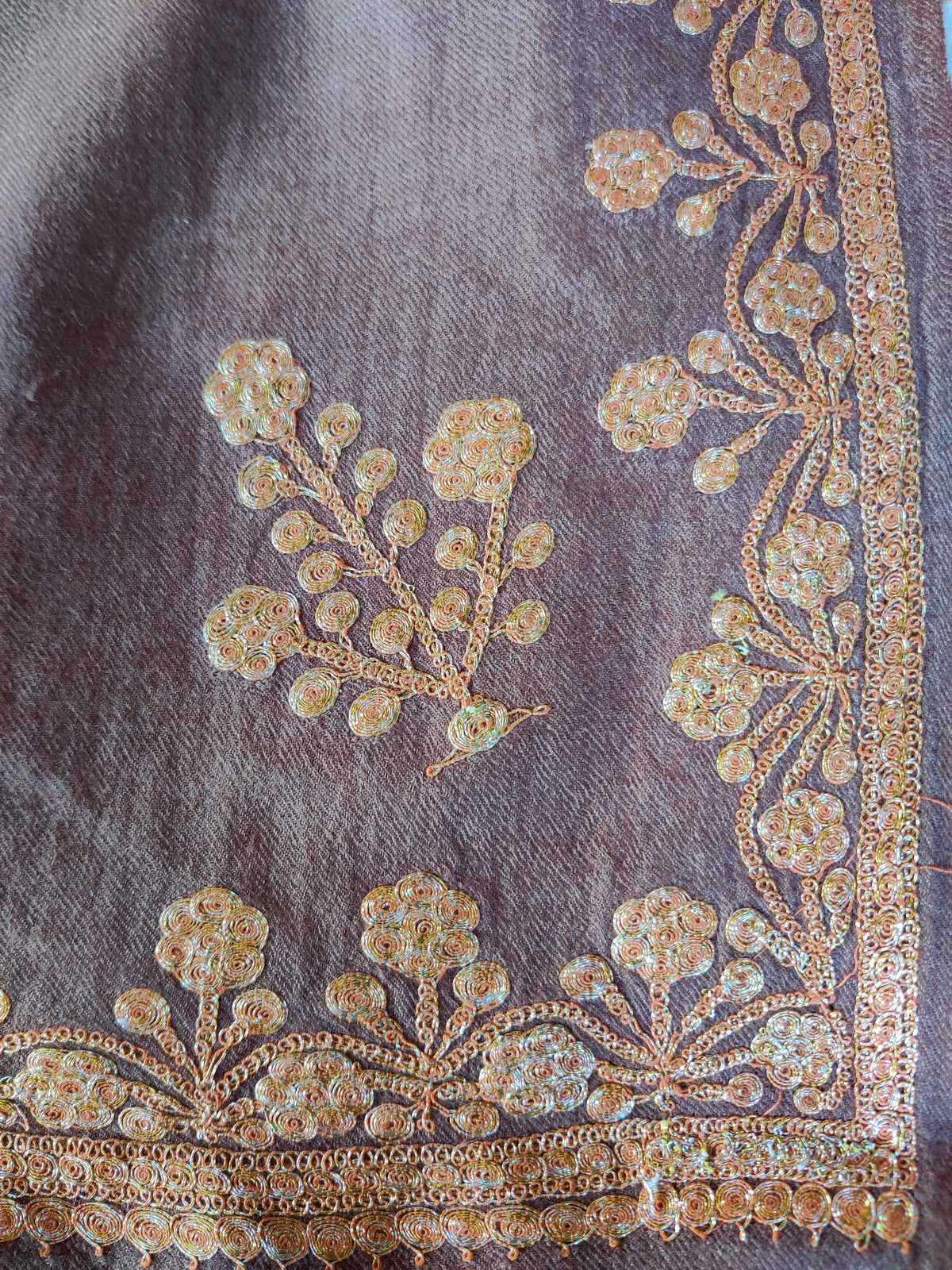 Flat corner detail of a brown Merino wool stole with gold-toned Tilla flowers, round leaves and narrow stitched edging