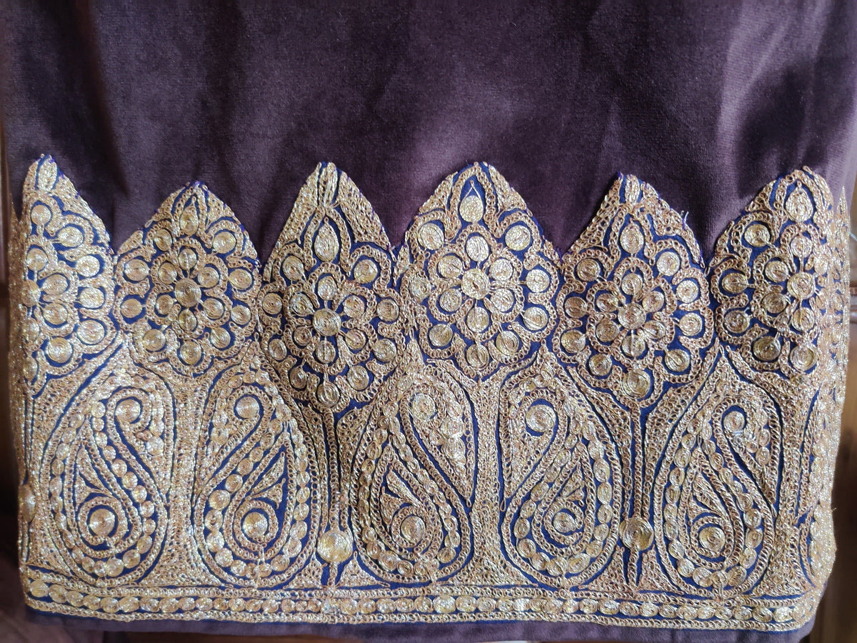 Close-up of the plum velvet pheran's hem, with gold-toned Tilla paisleys and circular flowers inside pointed scalloped panels.