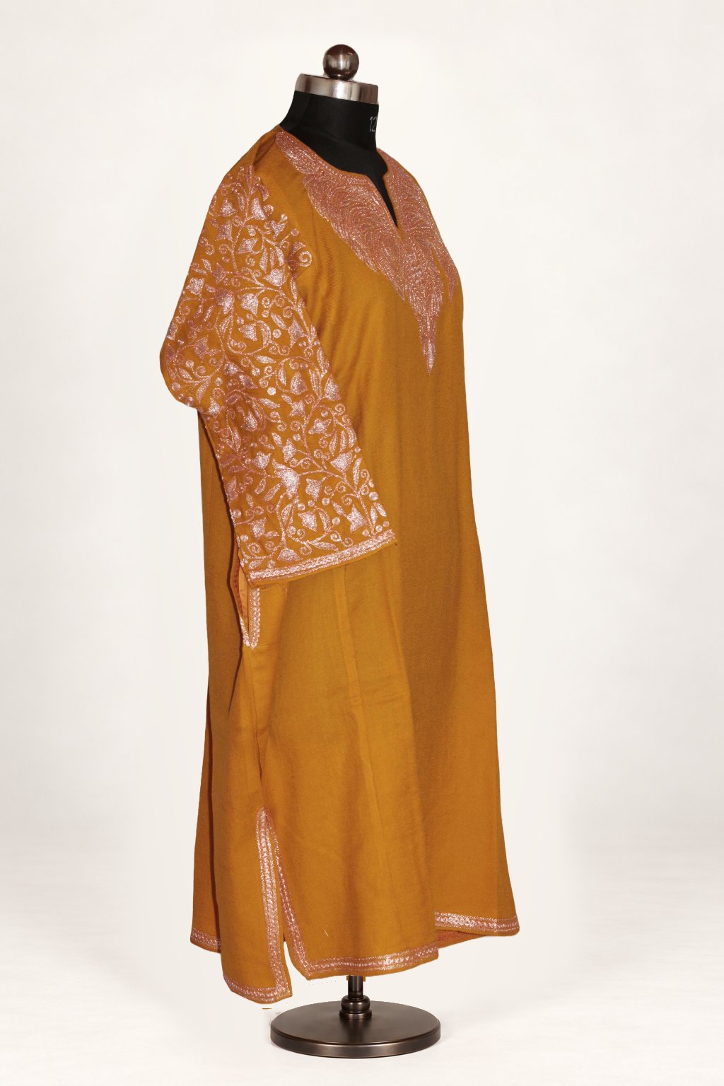 Three-quarter view of mustard pheran with pale pink Tilla embroidered neckline and sleeves, side slit and narrow hem trim