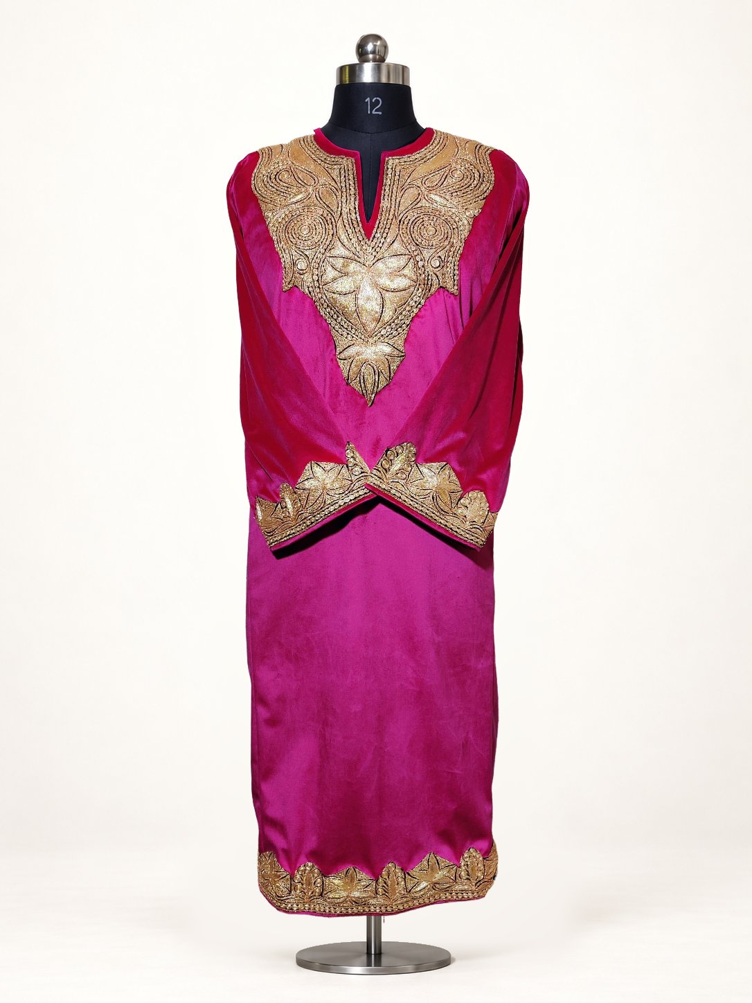 Pink velvet pheran on a mannequin, with golden Tilla floral embroidery around the neckline, crossed cuffs and hem
