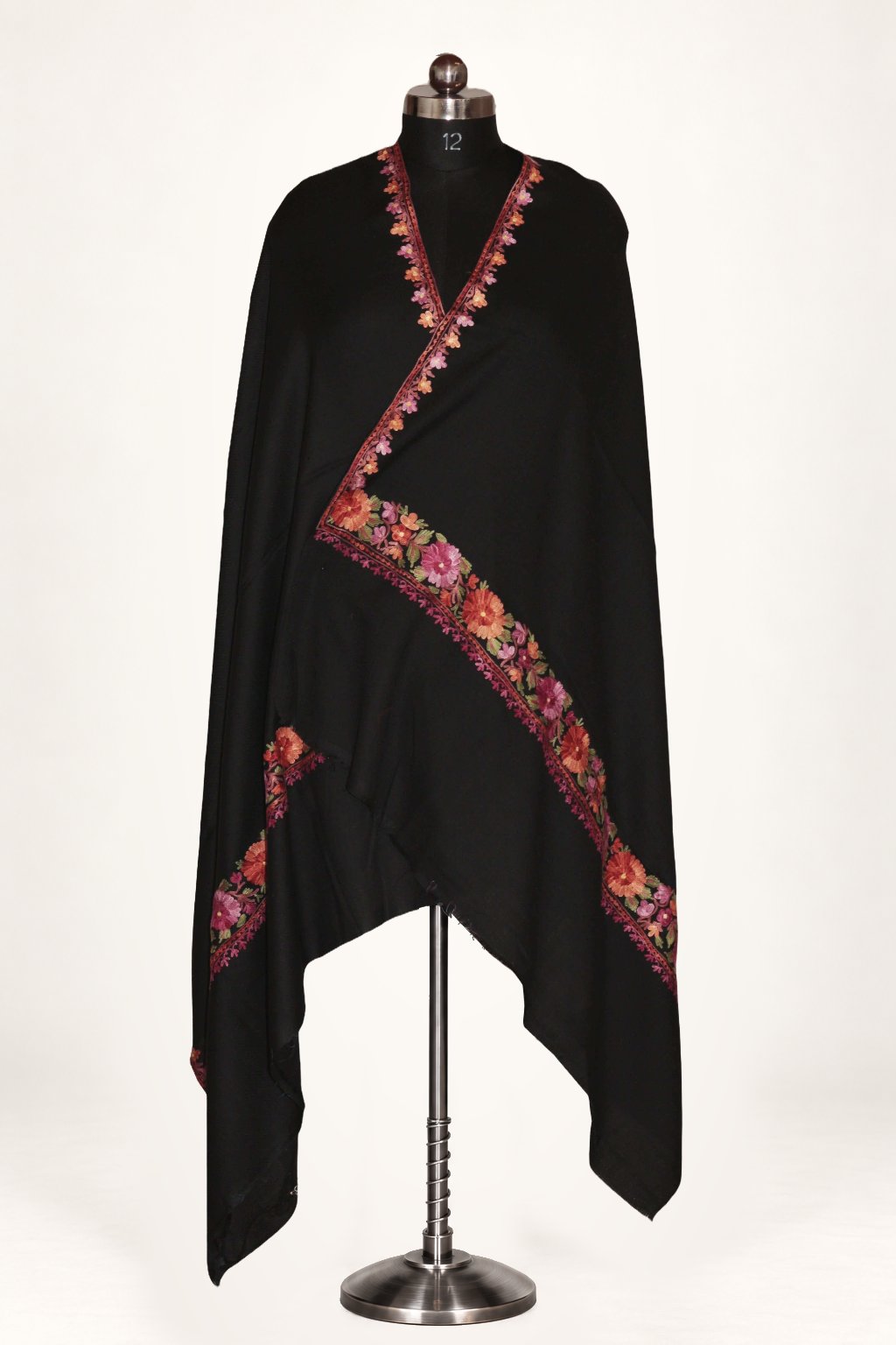 Black Merino wool shawl wrapped around a mannequin, with pink and orange Aari flowers along the borders