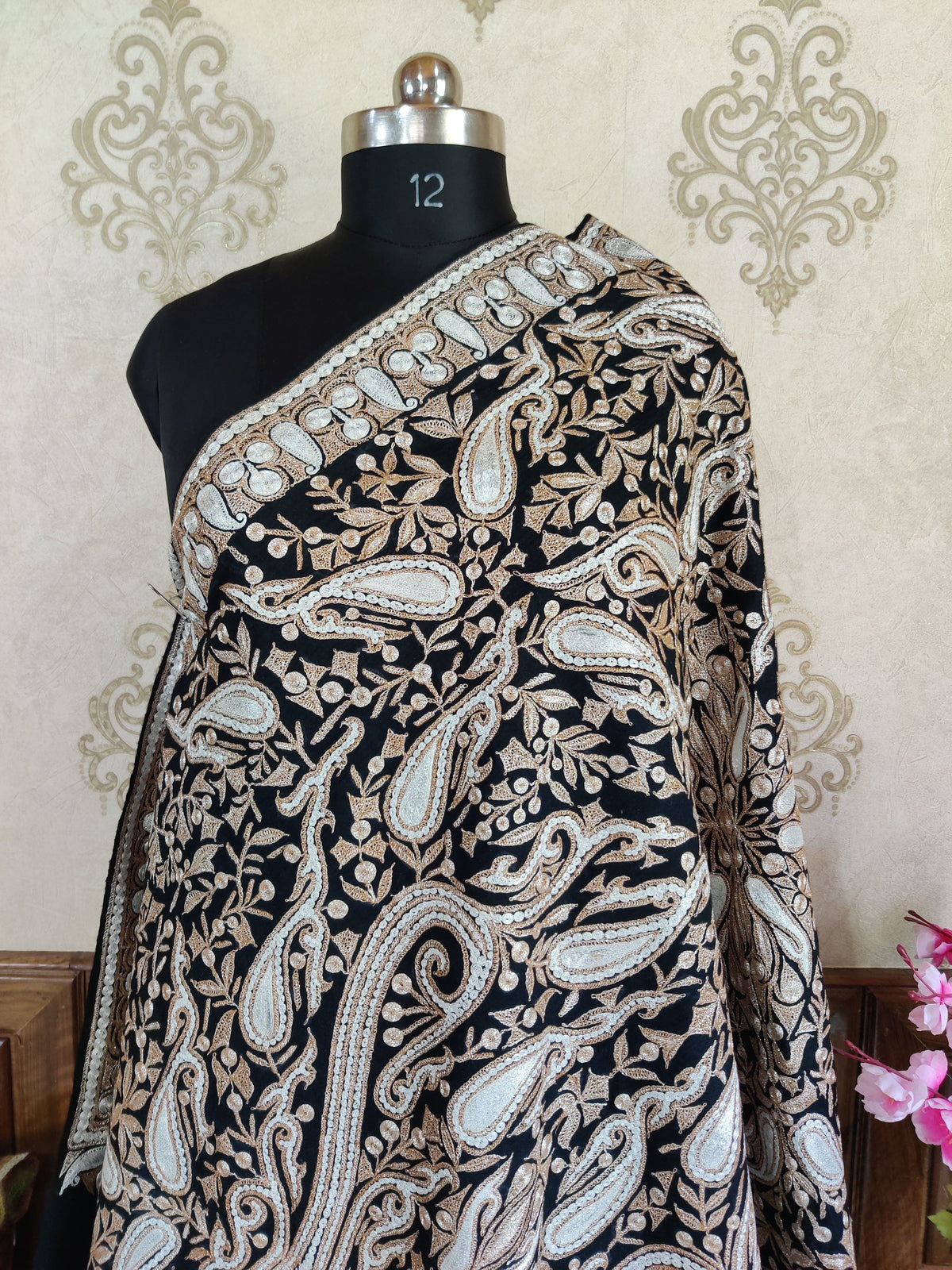 Upper view of the black Merino wool shawl draped diagonally across a mannequin, showing its paisley border
