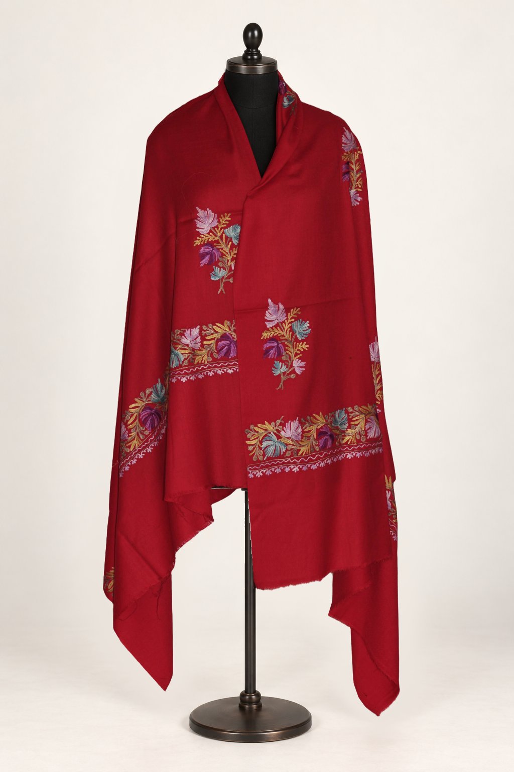 Red Merino wool shawl wrapped around a mannequin, with multicoloured Aari floral sprigs and embroidered end borders