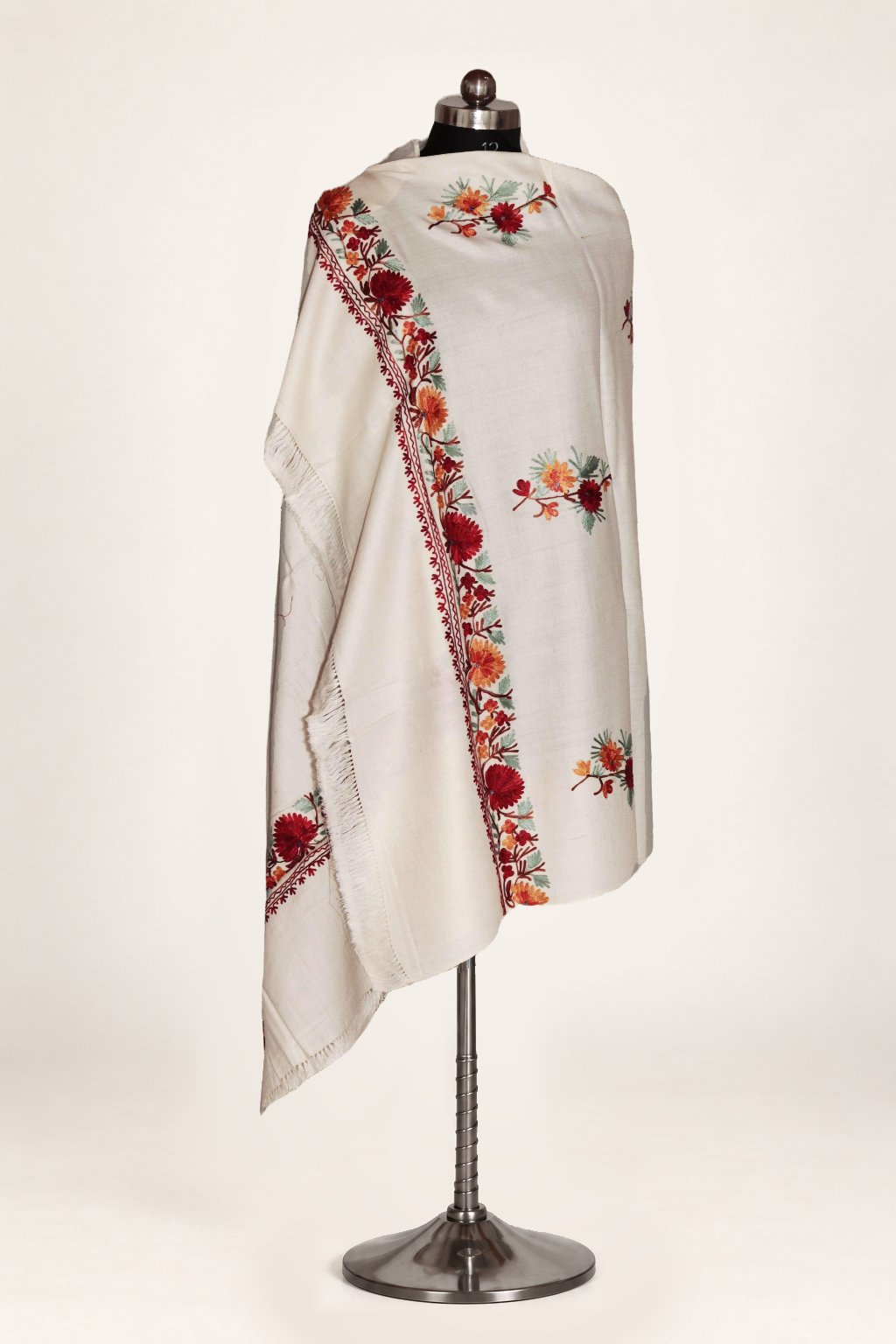 Full draped view of the white Merino wool shawl on a mannequin, with red and orange Aari floral sprigs and a matching narrow border