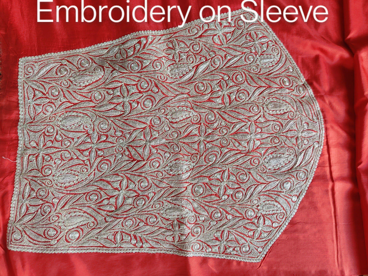Close-up of a dense silver-toned Tilla floral sleeve panel on red silk, labelled Embroidery on Sleeve