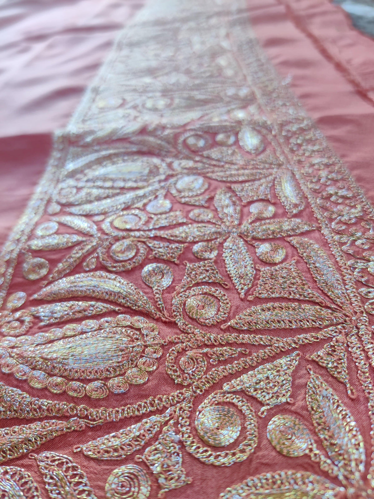 Close-up along the coral-pink silk border, showing pale-gold floral Tilla embroidery.