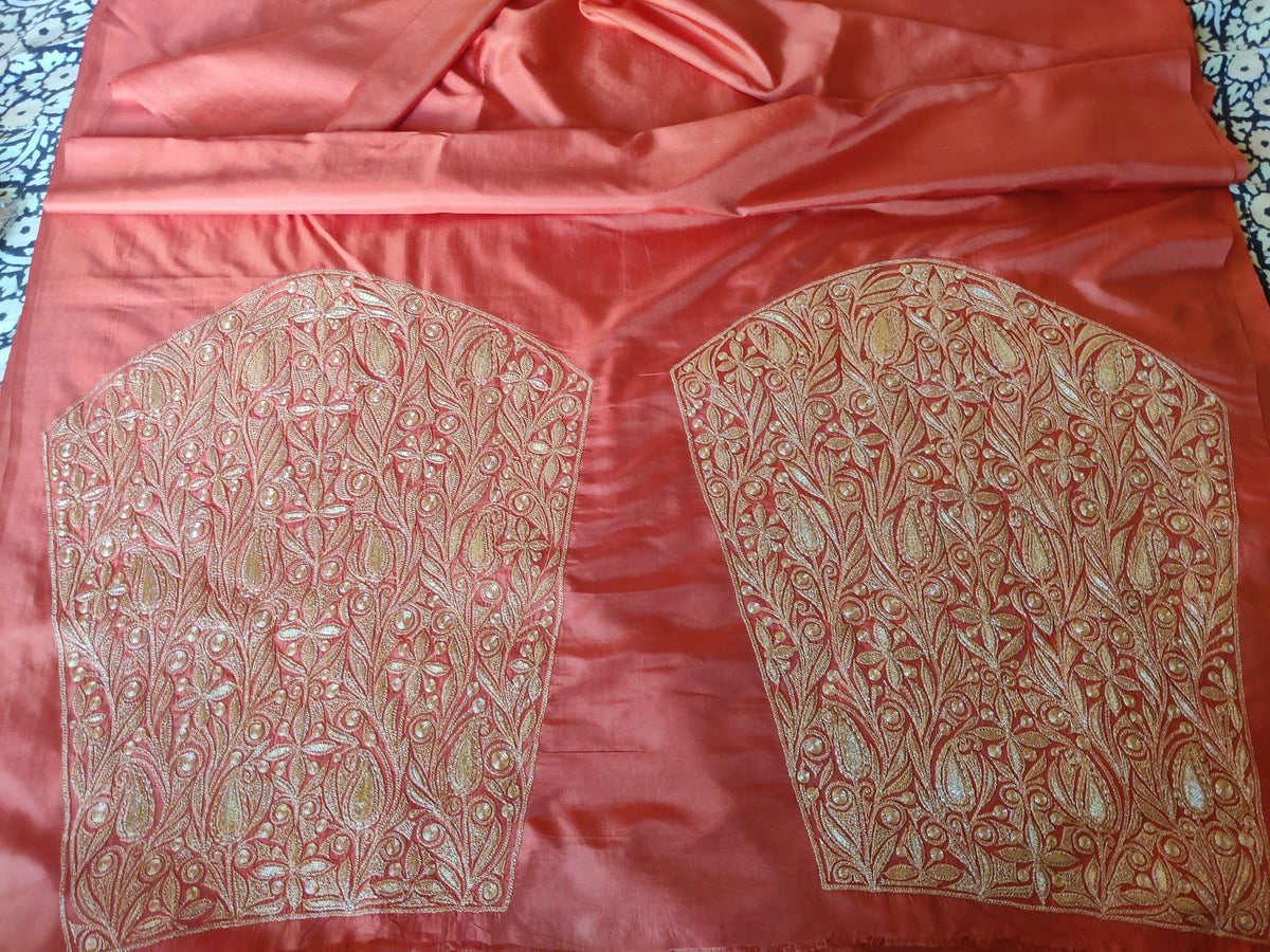 Two densely embroidered sleeve panels laid side by side on coral-pink silk fabric.