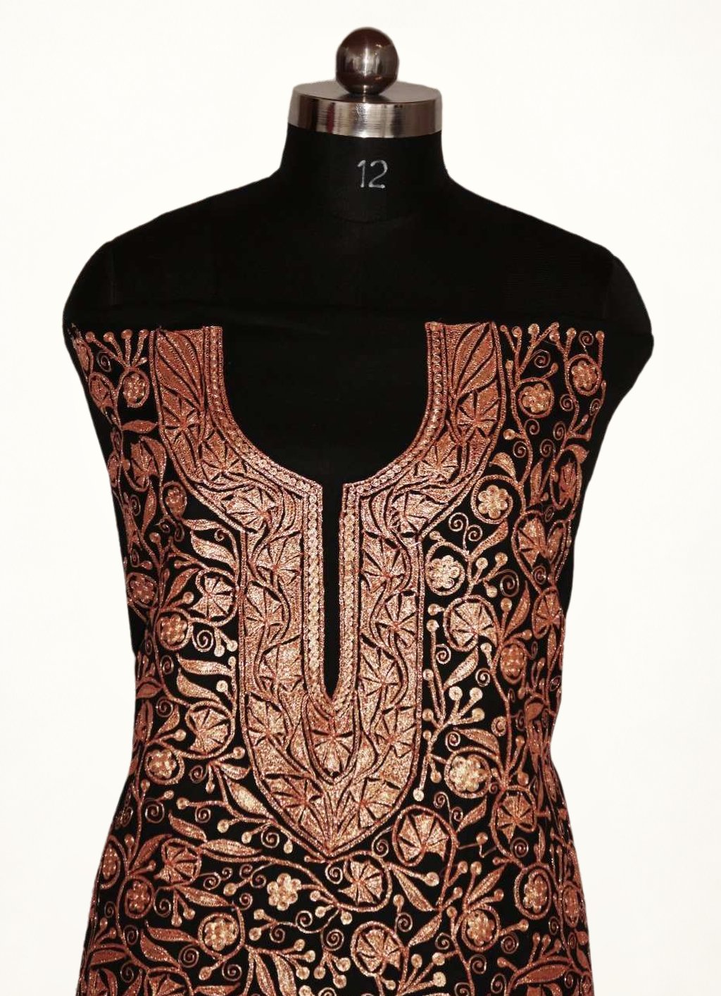 Close-up of black suit fabric with a copper-toned Tilla embroidered split neckline surrounded by floral vines