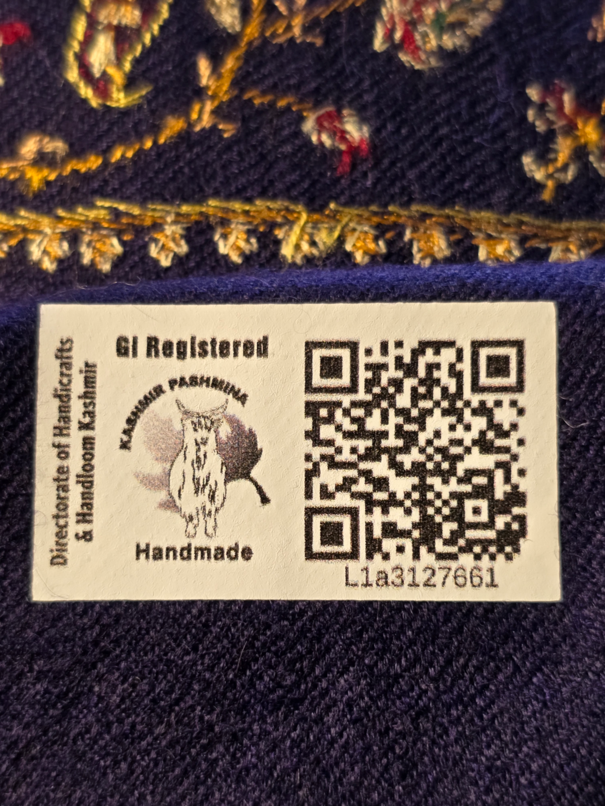 Kashmir Pashmina GI label marked Handmade, with a QR code below the golden embroidered border on blue fabric