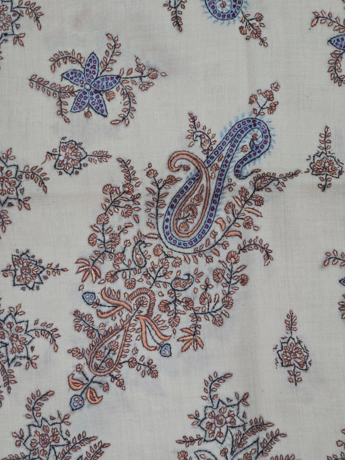 Close-up of a blue-edged paisley surrounded by brown scrolling leaves and small floral motifs on cream Pashmina