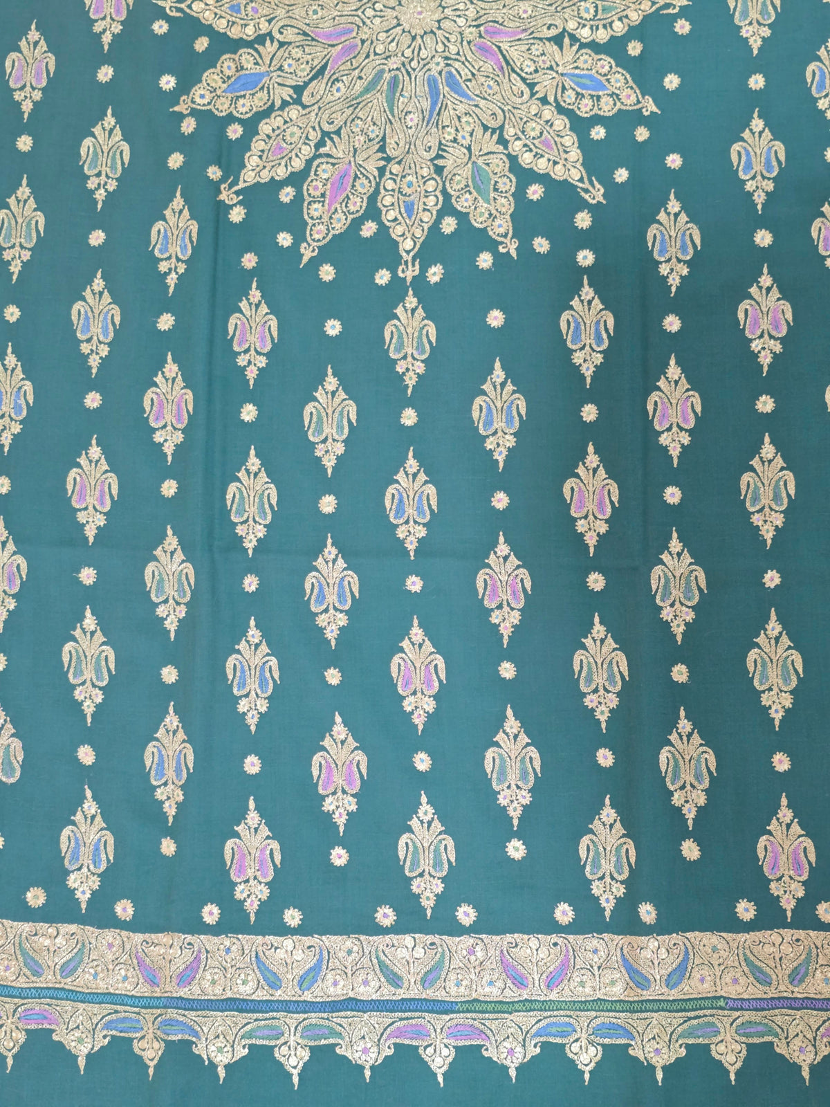 Emerald-green Pashmina shawl end detail with rows of gold motifs, blue and lilac accents and an ornate embroidered border