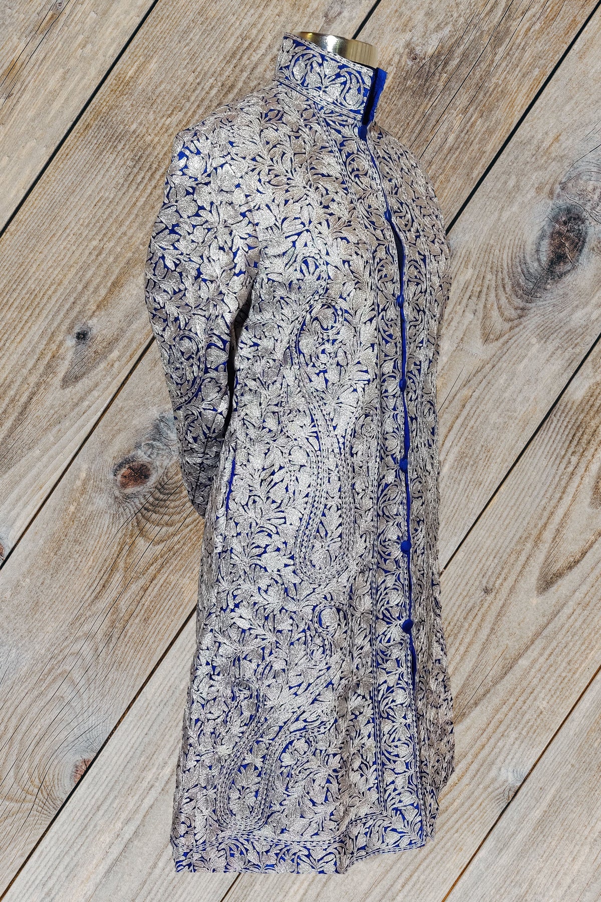 Three-quarter view of the deep blue Aari jacket on a mannequin, showing silver-toned floral embroidery and a standing collar.