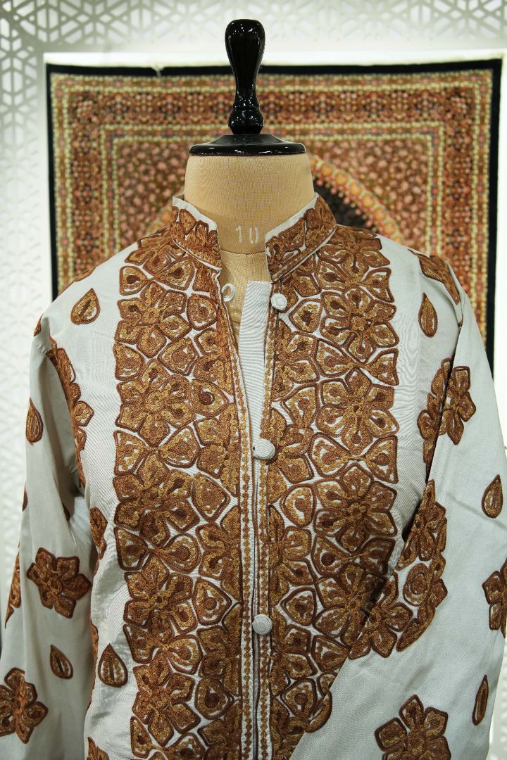 Upper front of an ivory jacket with copper-brown floral embroidery around the stand collar and front opening.