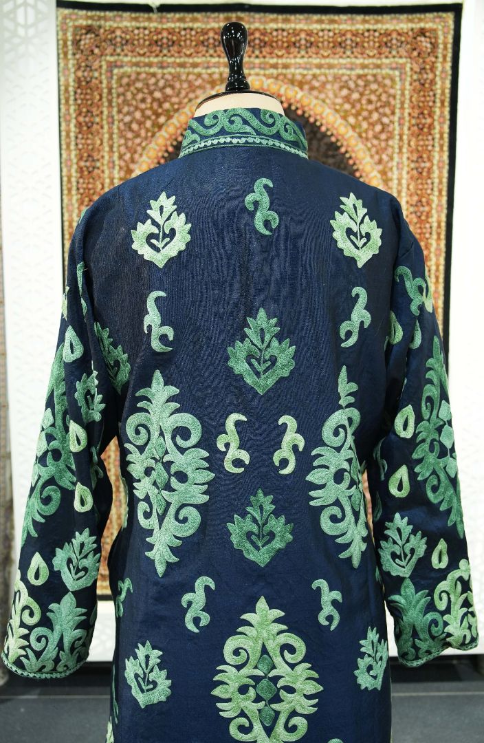 Upper back of the navy jacket with scattered green leaf motifs and larger symmetrical leafy scrolls
