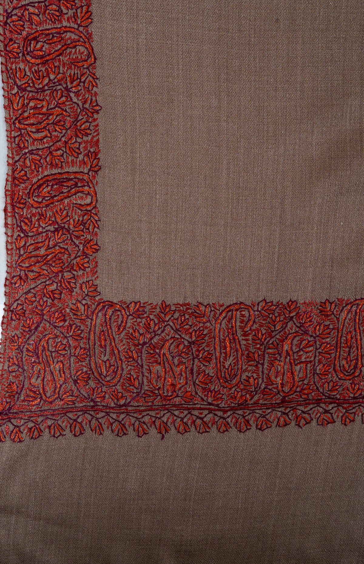 Mocha shawl corner with rust embroidered paisleys and leaf edging above a plain end