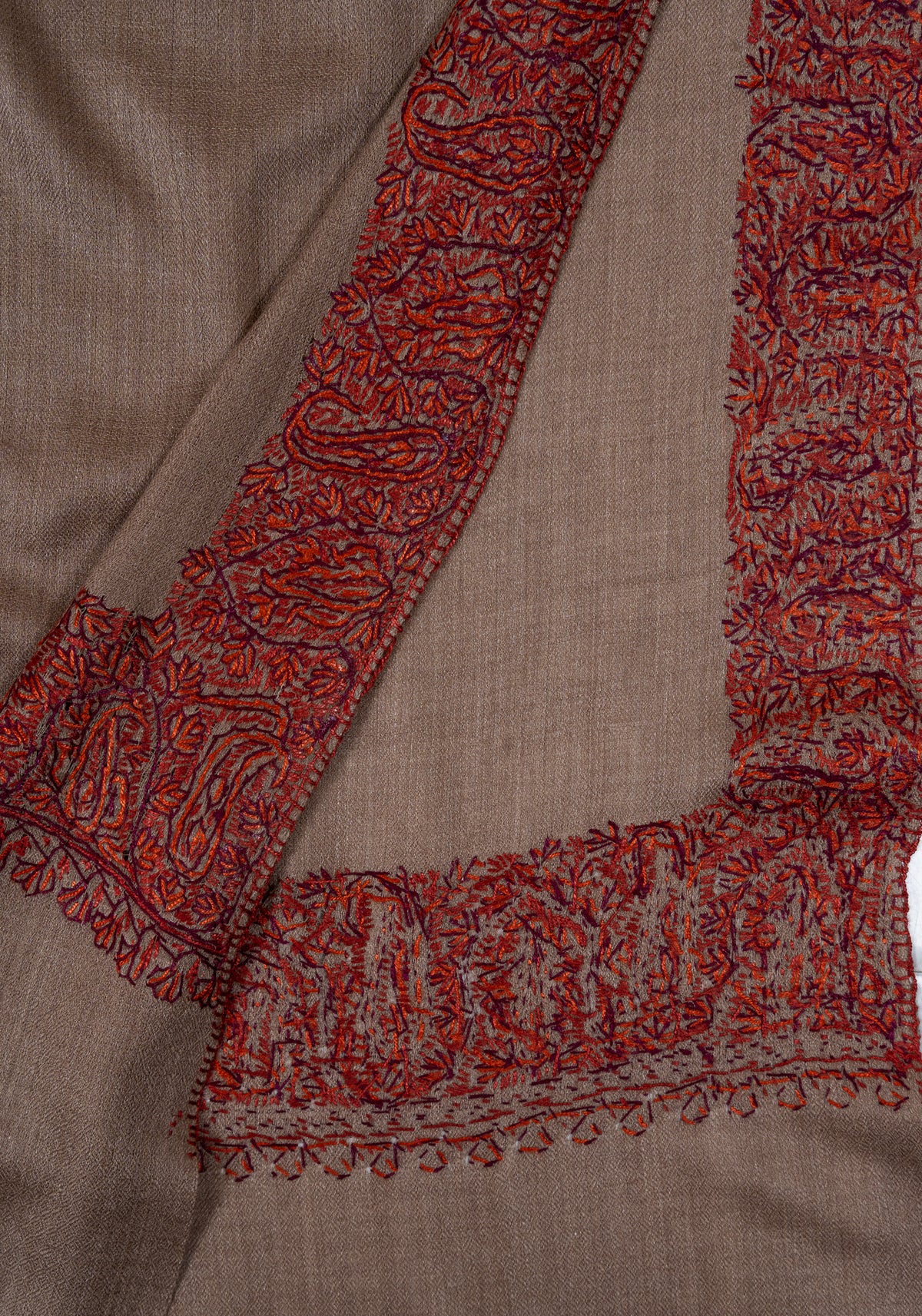 Overlapping mocha shawl corners showing the front and reverse of the rust embroidered borders