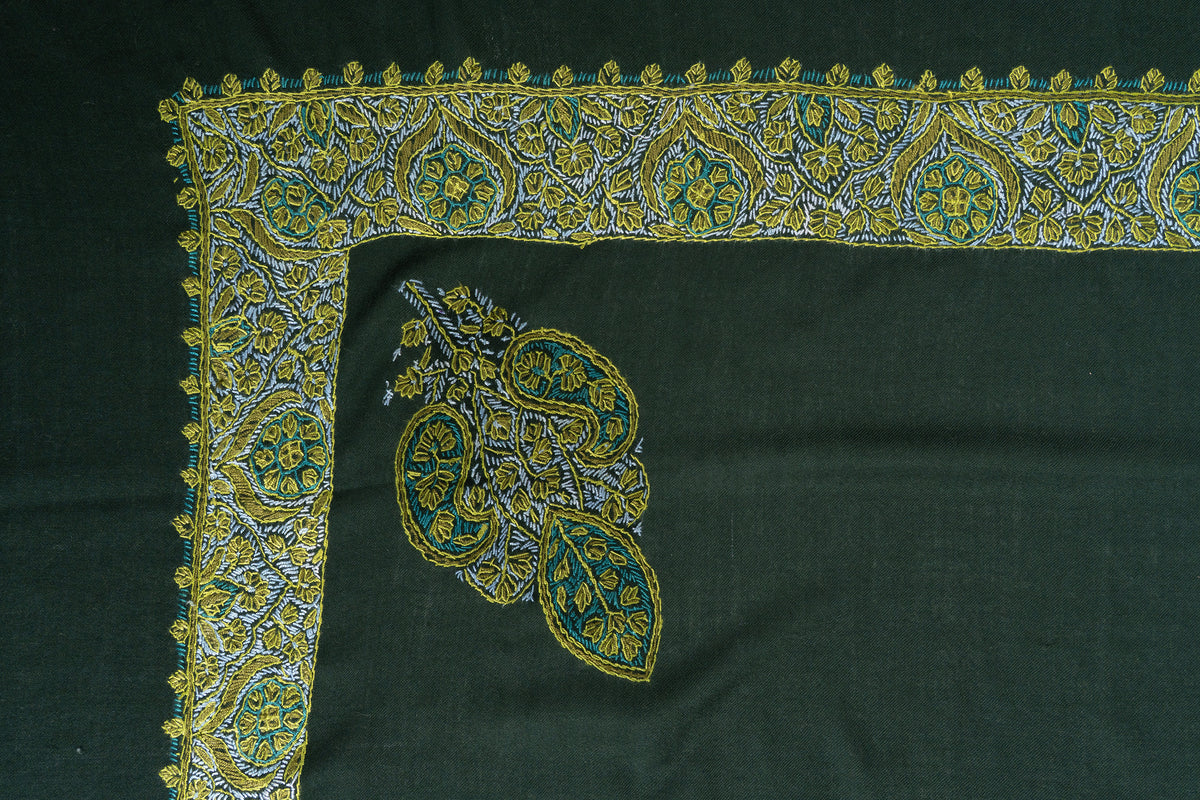 Flat corner of the emerald rumal showing a gold, ivory and teal paisley border beside a smaller floral paisley motif