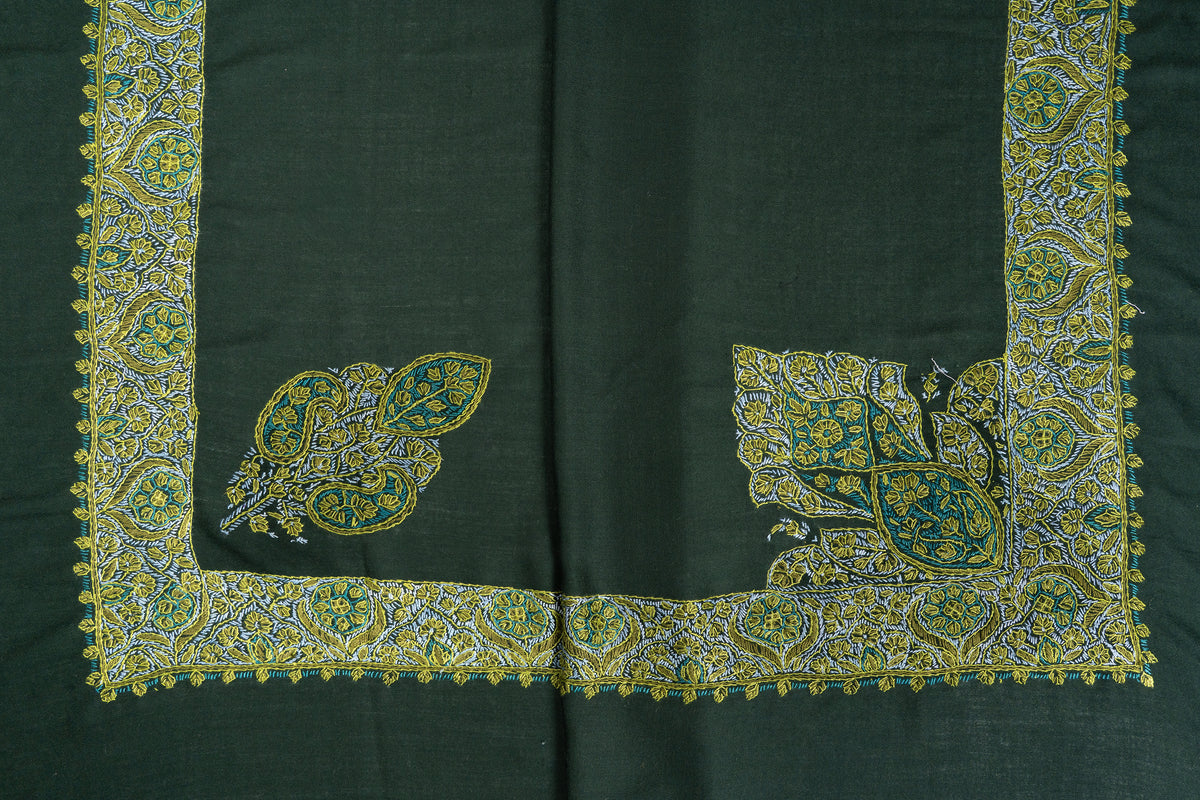 Folded green rumal showing two different corner motifs above the gold, ivory and teal Sozni border