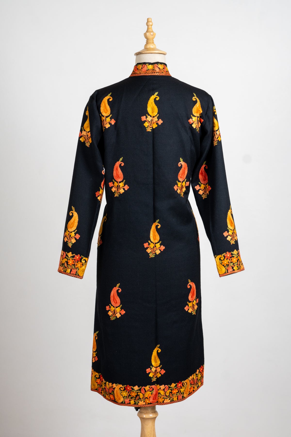 Full back of the black jacket with scattered gold and orange paisley sprigs and a colourful floral hem