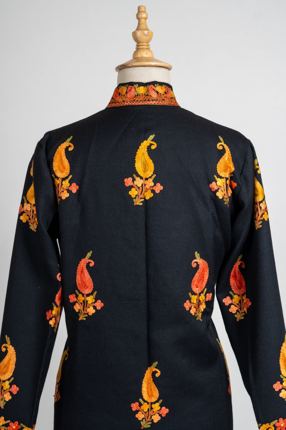 Upper back of the black jacket with scattered golden and orange paisley sprigs and an embroidered collar